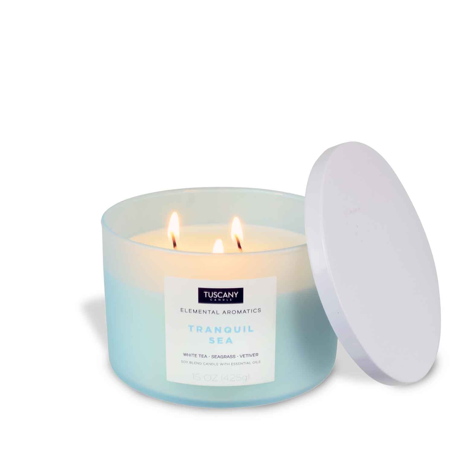A Tranquil Sea scented candle with a white lid on an ocean-inspired white surface, from the Tuscany Candle® EVD brand.