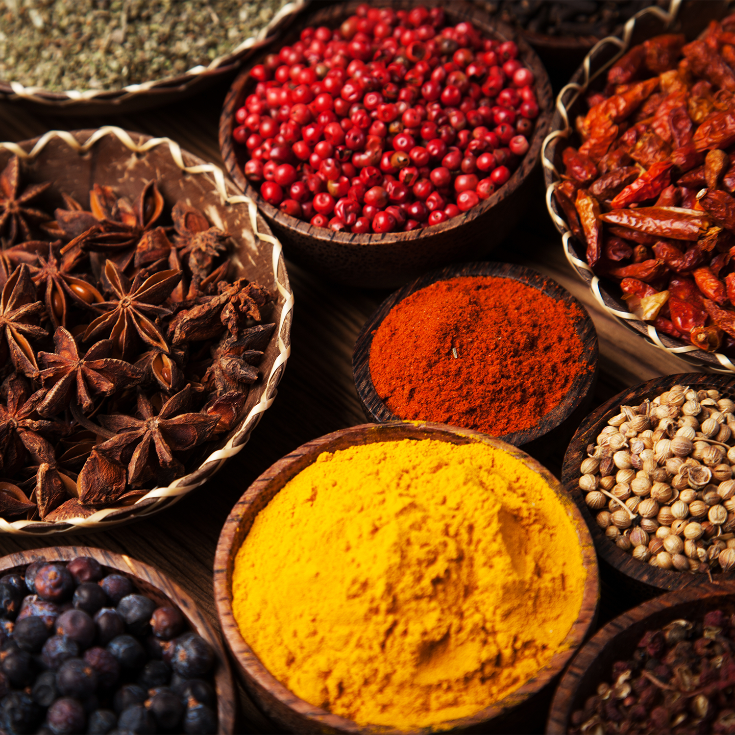 An assortment of exotic spices in bowls on a table, creating a warm and inviting atmosphere reminiscent of a Tuscany Candle Kitchen Spice Long-Lasting Scented Jar Candle (14 oz).