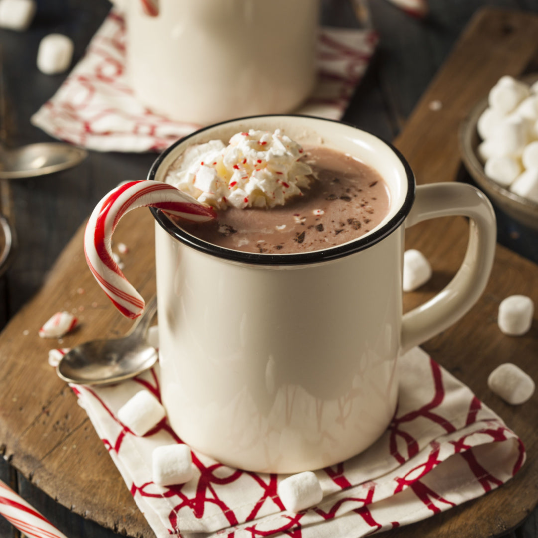 12oz Peace & Joy scented candle in a glossy white glass jar with a gold lid, emanating a harmonious blend of peppermint, hot cocoa, and sugared vanilla from the Winter candle collection.
