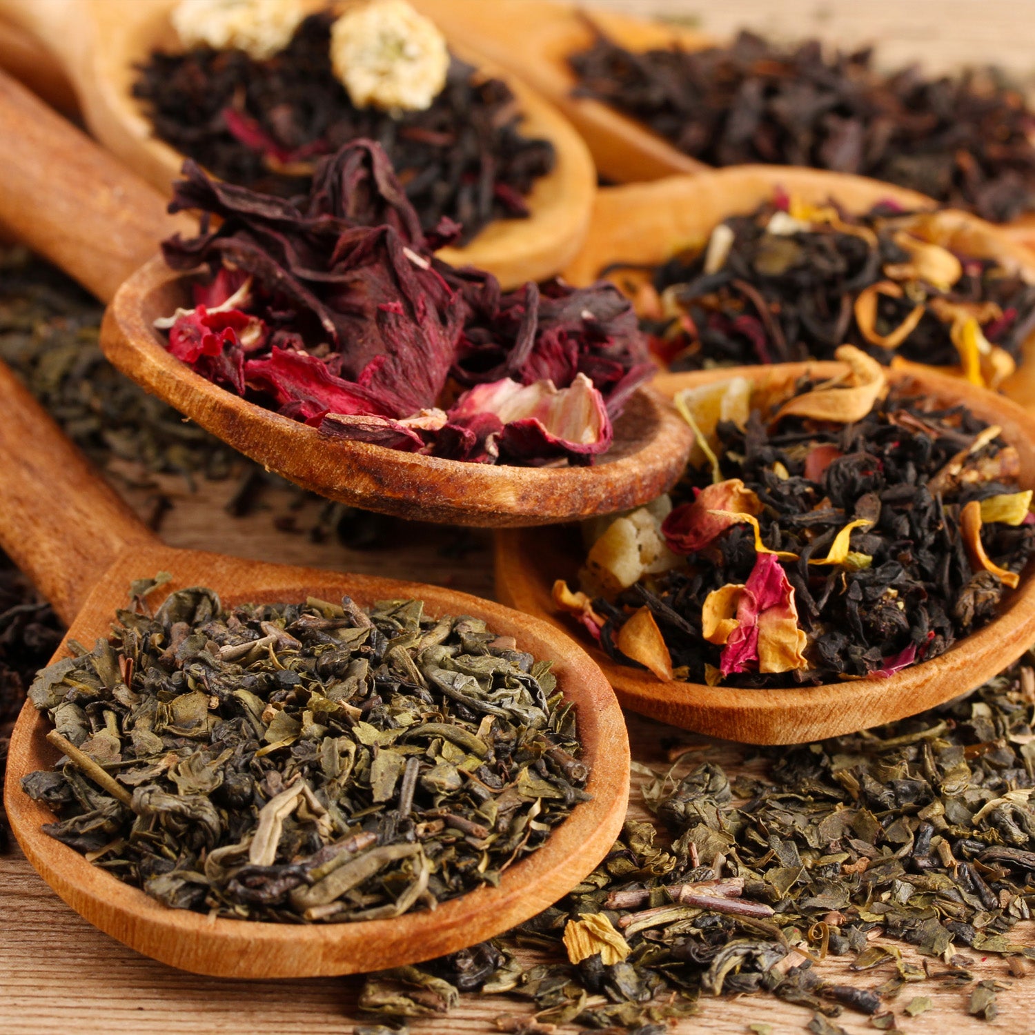 Dired tea leaves are shown being blended by wooden spoons. Tea is one of the primary notes in Tuscany Candle's "Tea Leaves" scented candle.