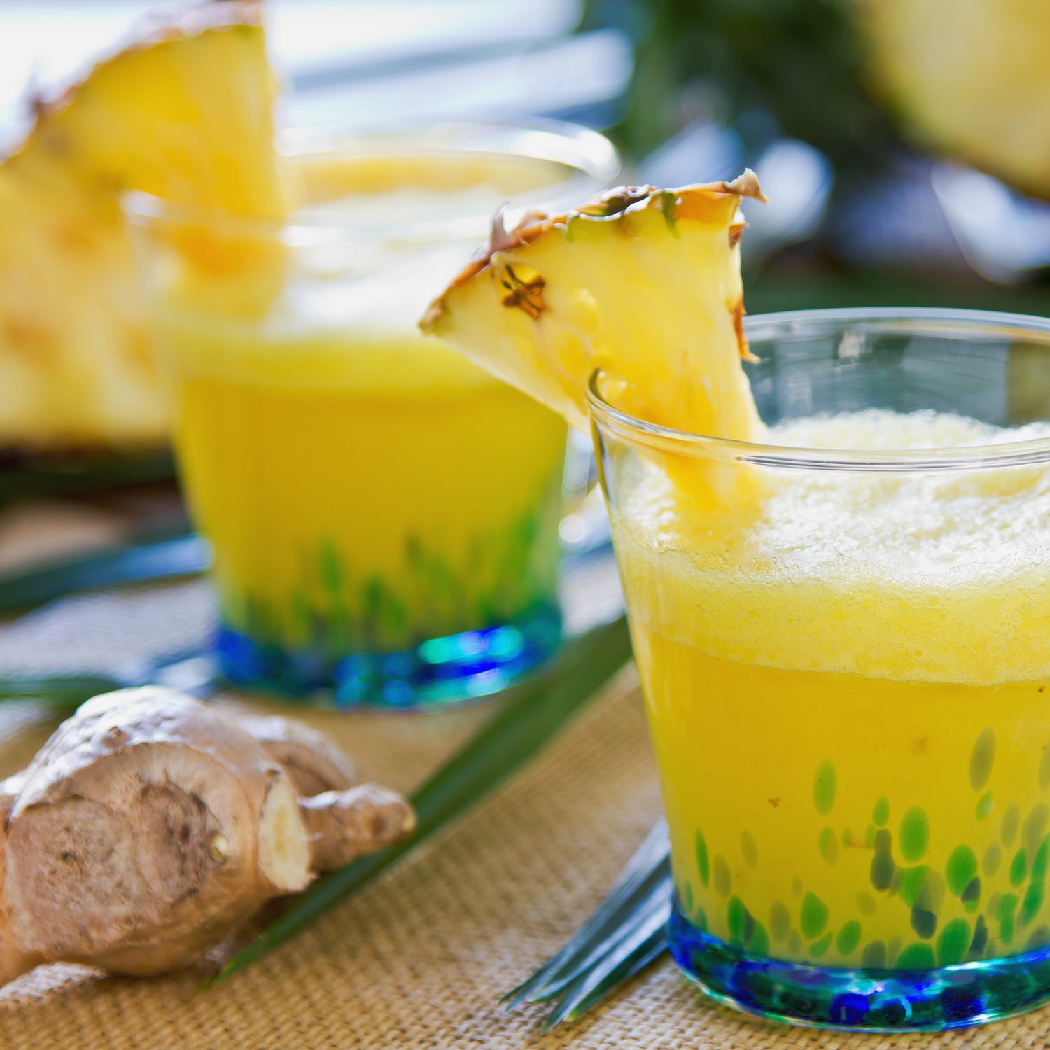 Two glasses of Pineapple Ginger Long-Lasting Scented Jar Candle (14 oz) infused with the fragrance of essential oils and a slice of ginger.