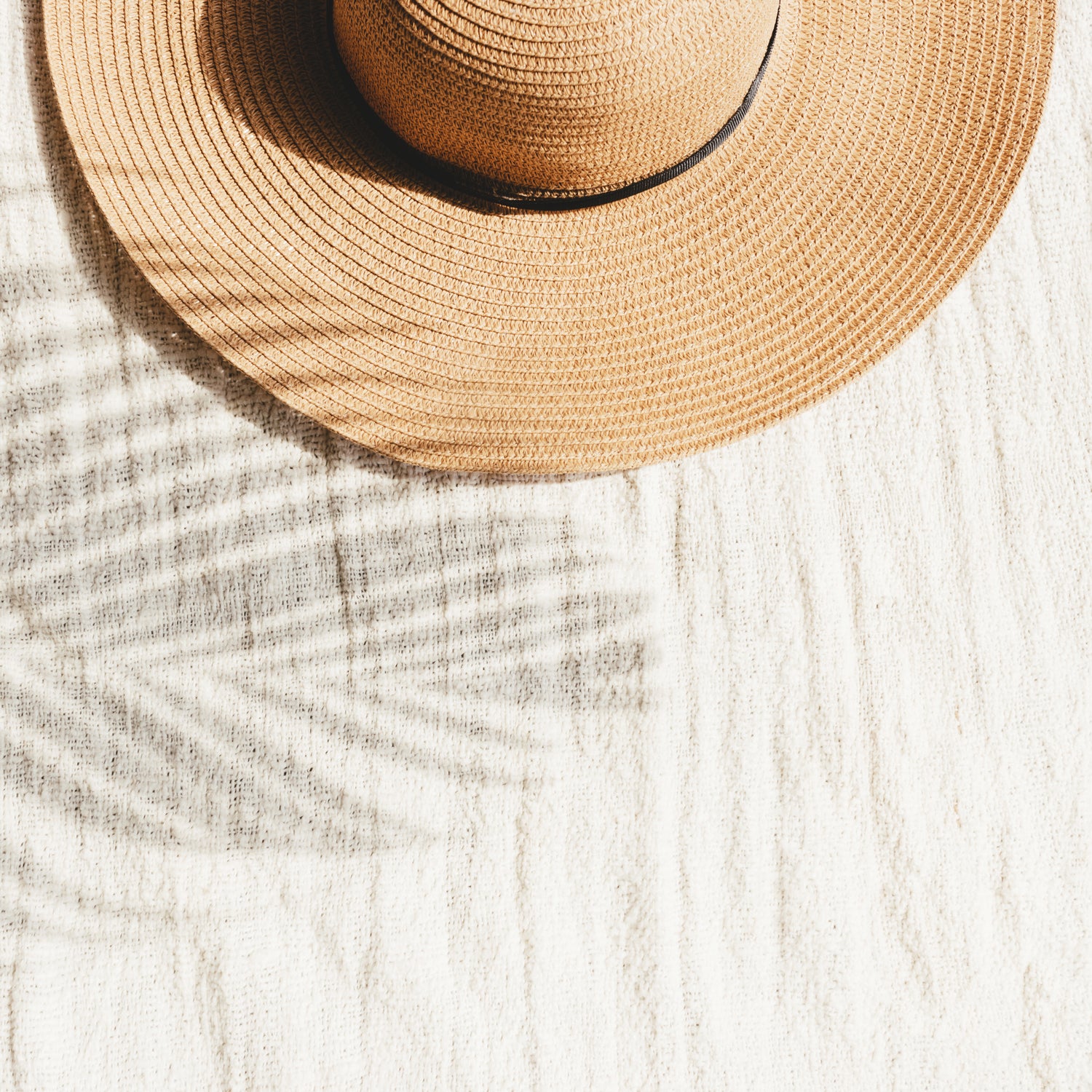 A straw hat resting on a beach - inspiration for our "Sea & Sand" fragrance
