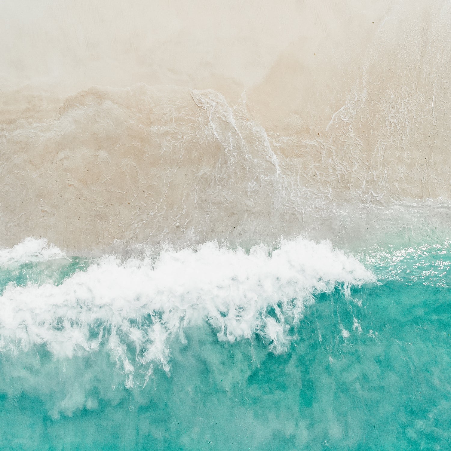 An aerial view of a beach with waves and white sand, featuring the Tuscany Candle Ocean Mist Long-Lasting Scented Jar Candle (14 oz).