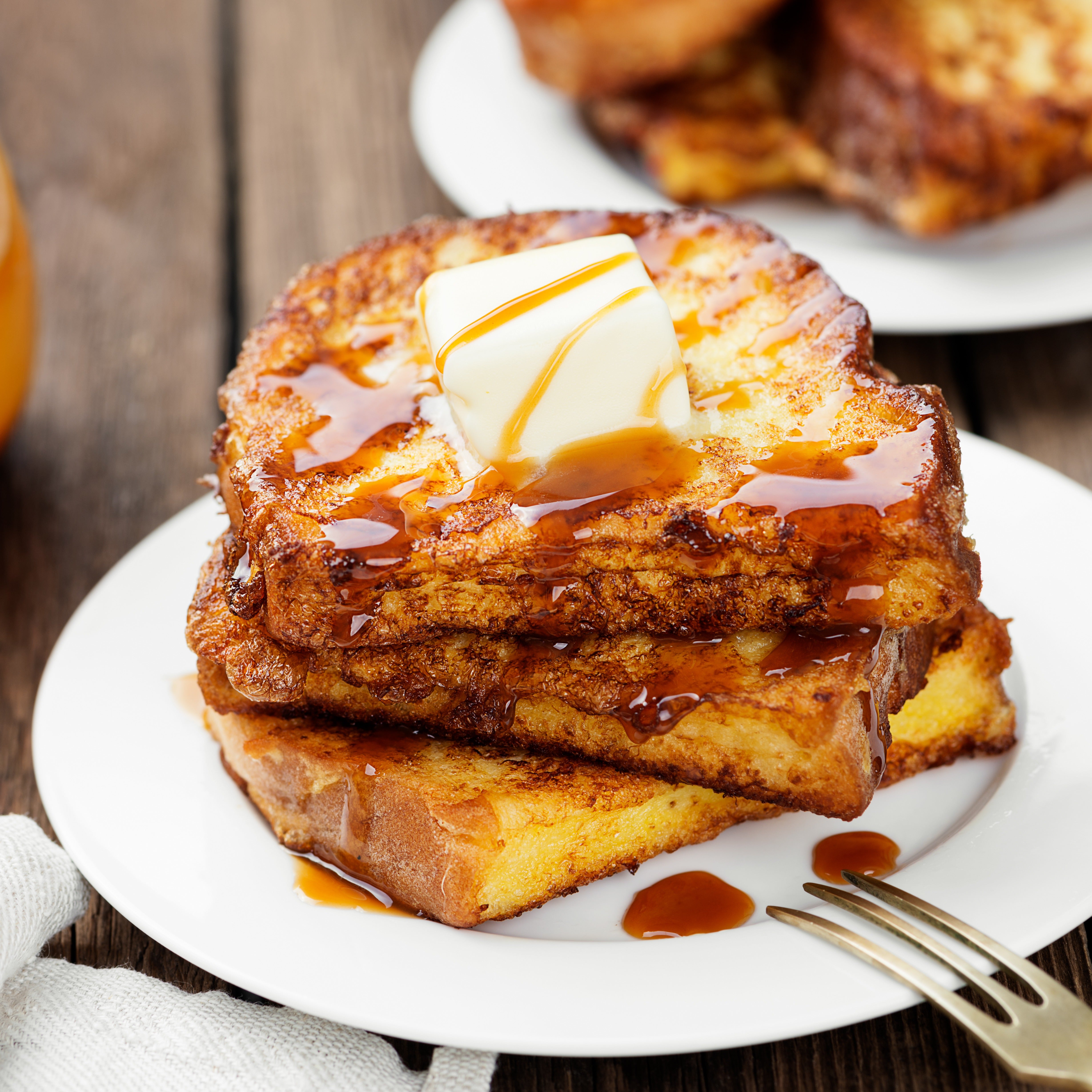 A stack of French Toast Scented Wax Melt (2.5 oz) tart bars from Tuscany Candle®, with butter and syrup on a plate.