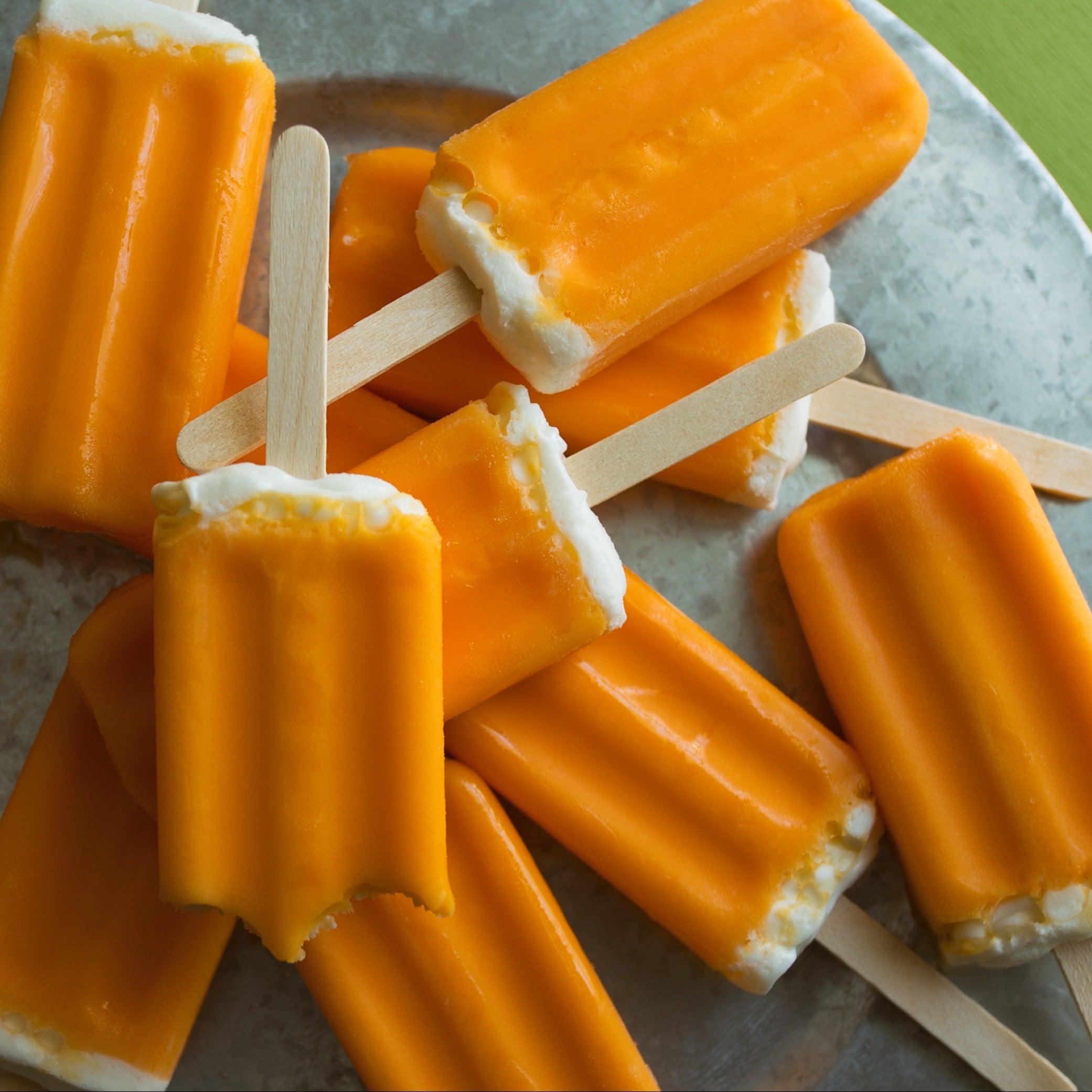 A Tuscany Candle® plate adorned with vibrant Orange Vanilla Scented Wax Melts (2.5 oz), offering a delightful and refreshing treat.