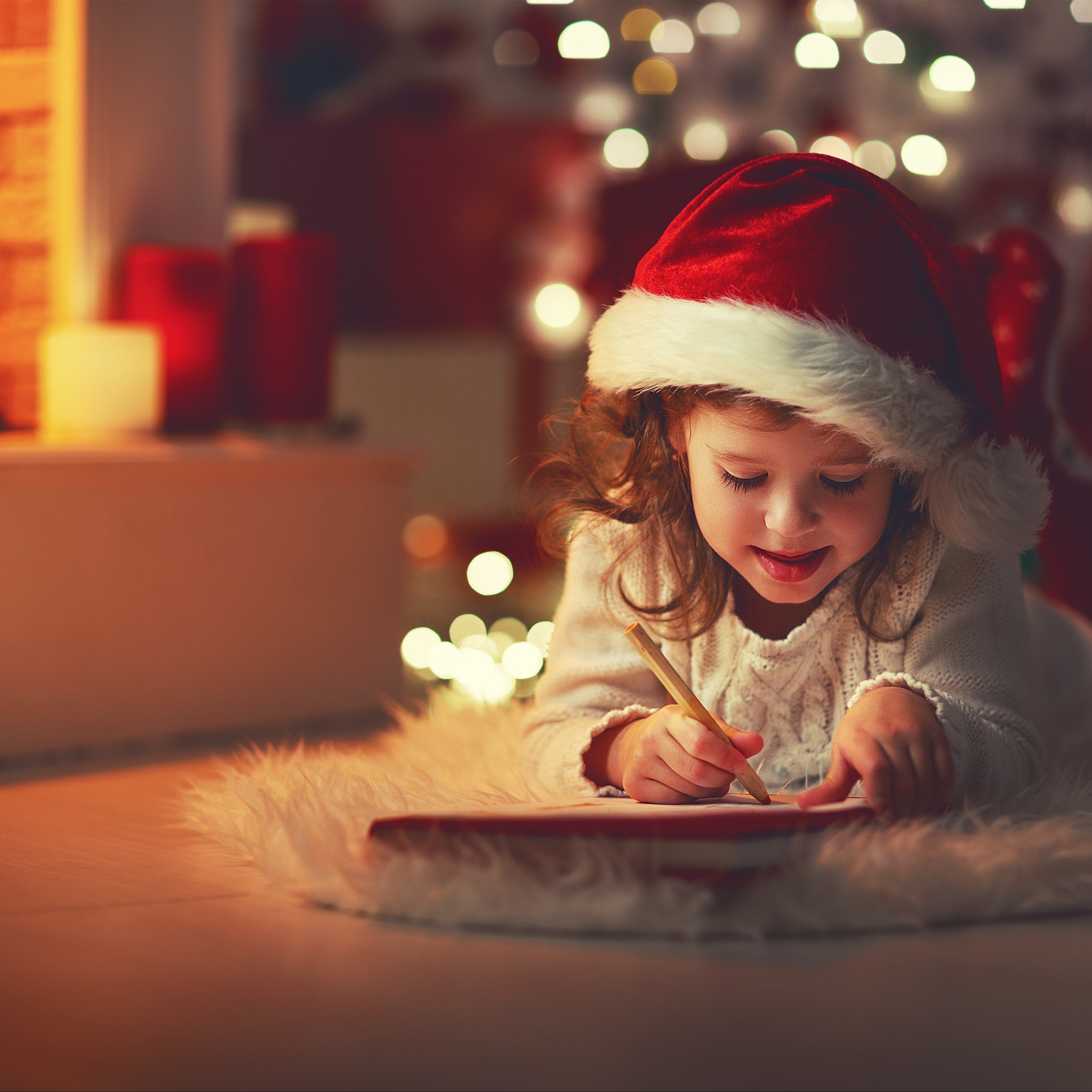 A little girl write a letter to Santa in front of a Christmas Tree - the inspiration for the fragrance in this wax melt bar