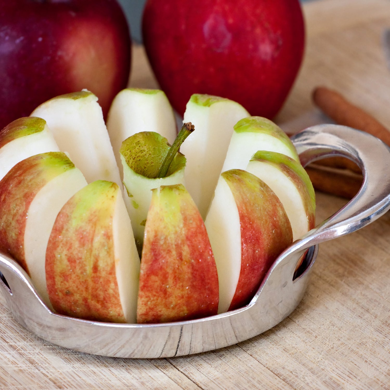 Sliced apples in a bowl with cinnamon sticks, evoking the fragrant aroma of a Tuscany Candle® EVD Orchard Apple Long-Lasting Scented Jar Candle (14 oz).