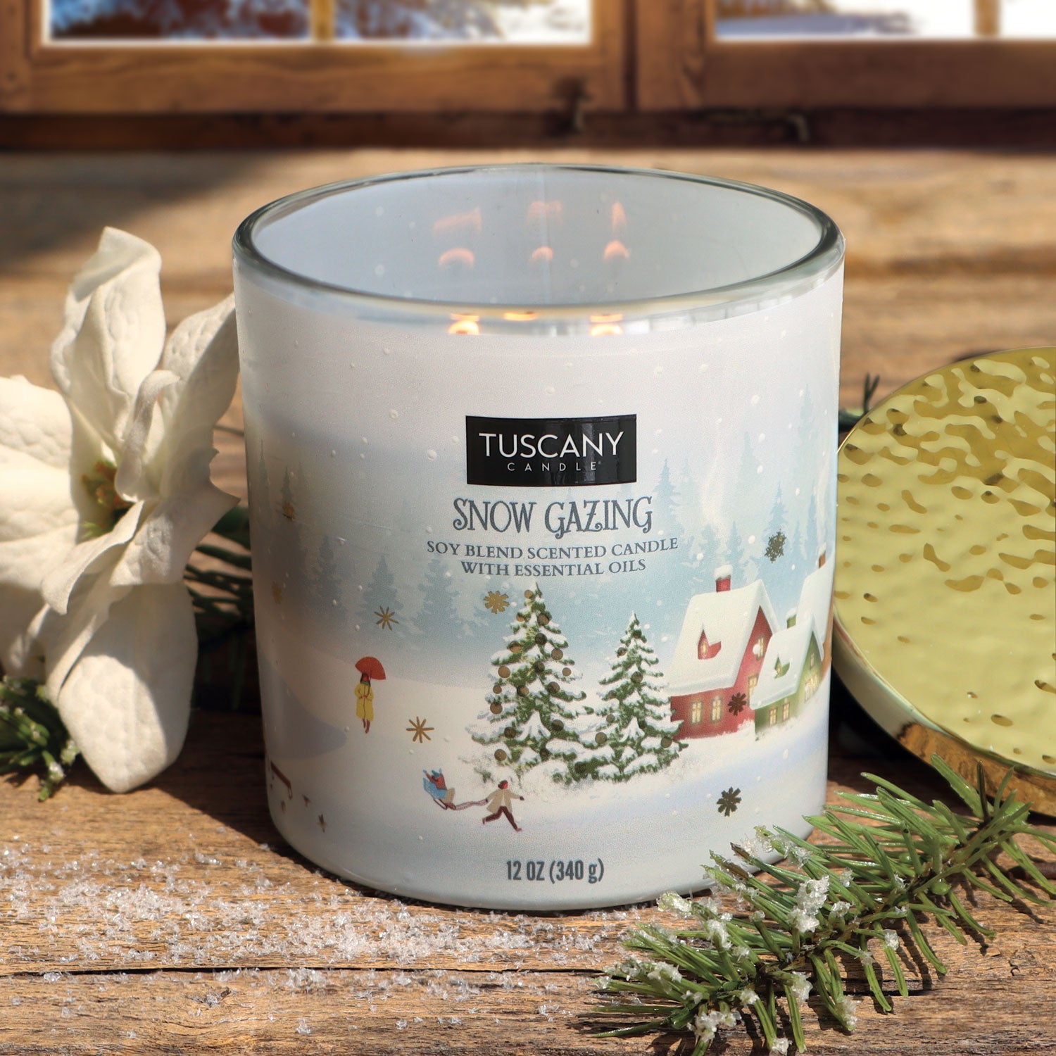 12oz Snow Gazing scented candle in a frosted glass jar with a gold lid, filled with white wax, emanating fragrances of fresh snow, soft woods, bergamot, and jasmine from the Christmas candle collection.