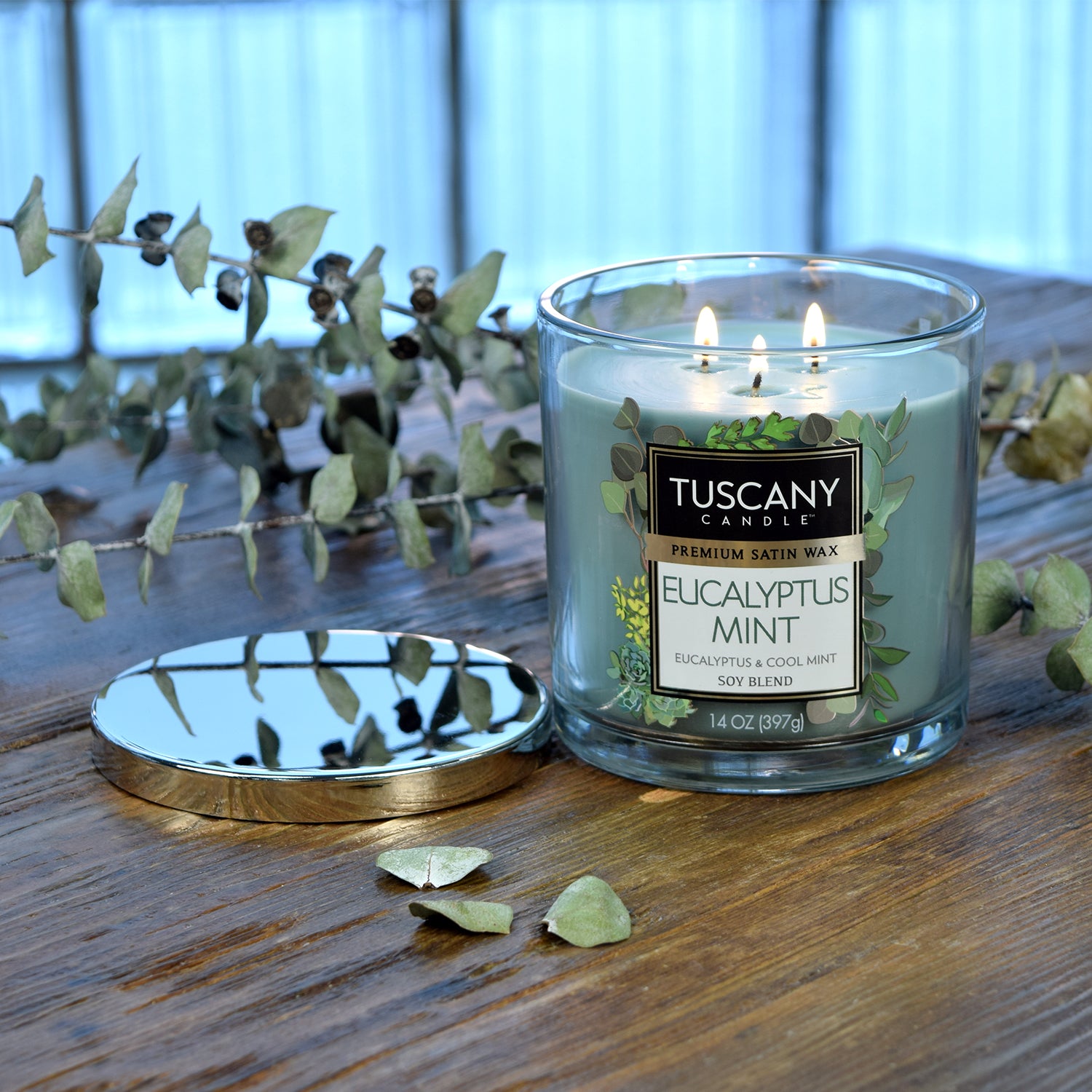 Eucalyptus Mint Long-Lasting Scented Tuscany Candle (14 oz) on a wooden table.