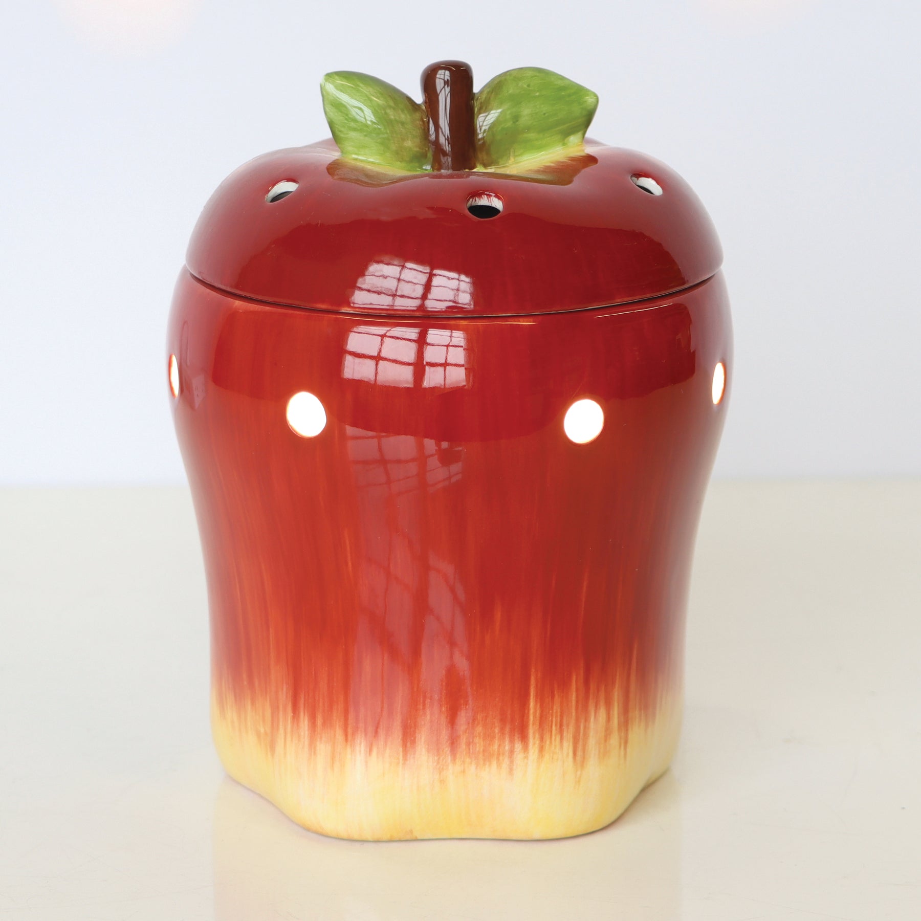 Ceramic container shaped like a red apple with green leaves as the lid's handle, perfect for storing Tuscany Candle® SEASONAL Apple Wax Melt Warmer.