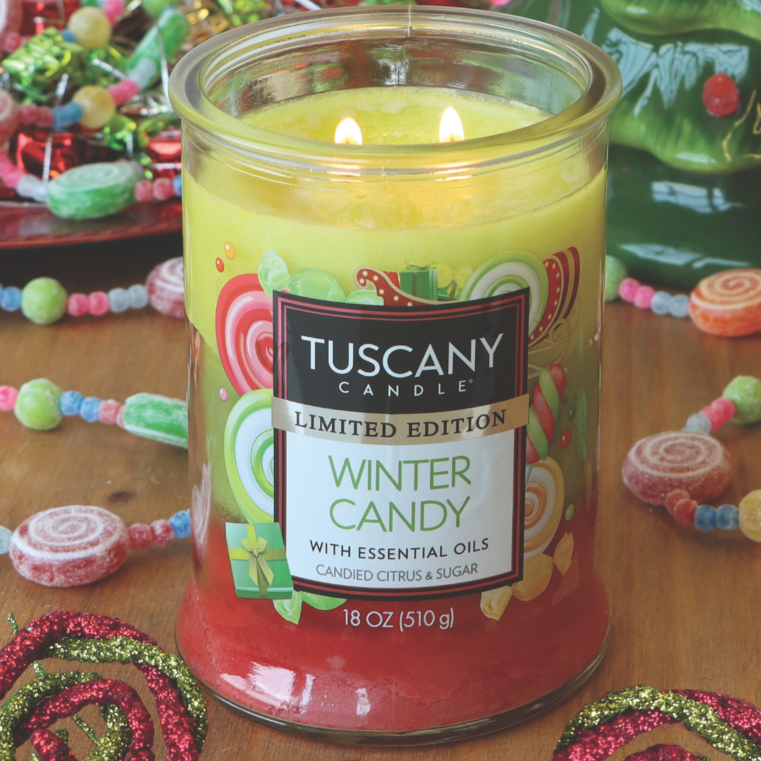 A lit "Winter Candy Long-Lasting Scented Jar Candle" by Tuscany Candle® SEASONAL, surrounded by colorful candy decorations. The label reads "Limited Edition" with a description of "Candied Citrus & Sugar.