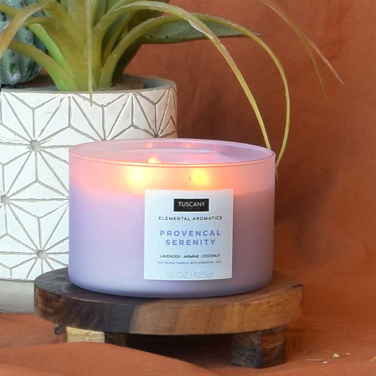A Provencal Serenity scented jar candle (15 oz) from the Elemental Aromatics Collection by Tuscany Candle is sitting on a wooden table.
