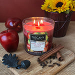 Load image into Gallery viewer, A gorgeous photo of Tuscany&#39;s candle&#39;s new &quot;apple Ginger Toddy&quot; scented candle. The candle is shown in the photo with an apple and other items that are part of the fall fragrances of this long-lasting candle
