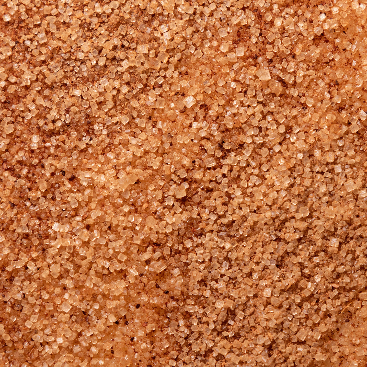 A close-up of raw brown sugar granules forming an uneven, textured surface evokes the delightful snickerdoodle scent found in Tuscany Candle® SEASONAL's Only Treats Scented Wax Melt (2.5 oz).