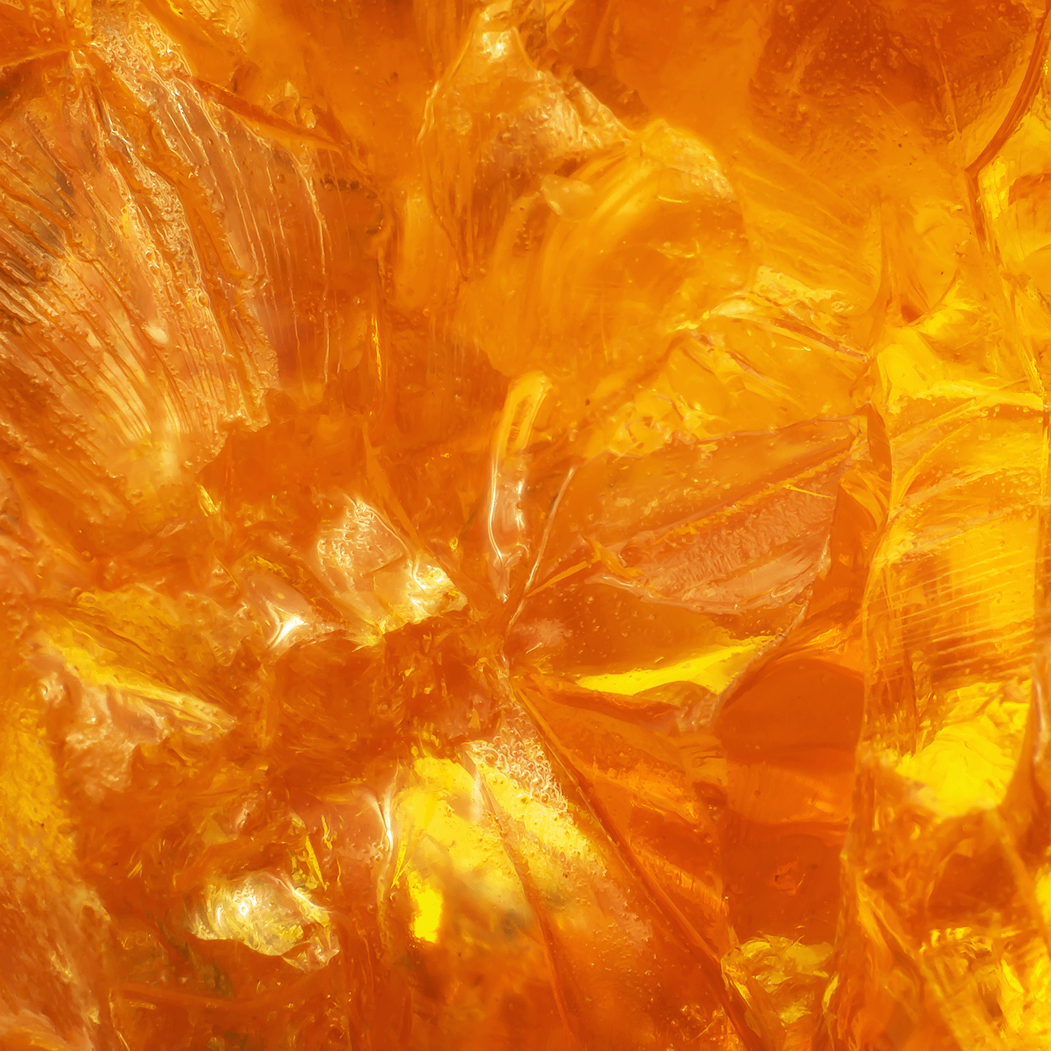 Close-up of translucent, amber-colored crystalline structures forming an abstract pattern with varying shades of orange and yellow, evocative of the warm hues found in the Haunted House Long-Lasting Scented Jar Candle (12 oz) by Tuscany Candle® SEASONAL.