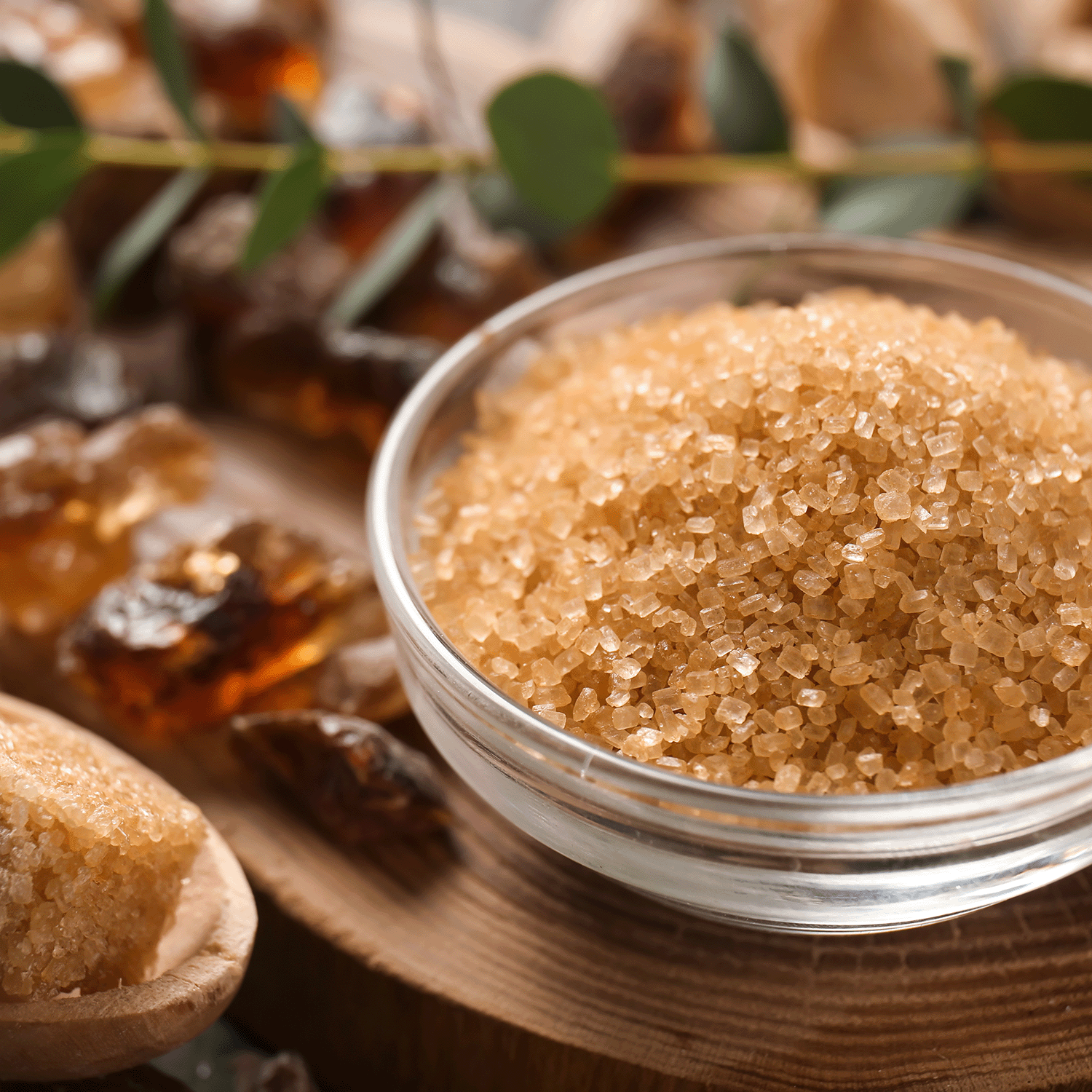 A Happy Harvest Long-Lasting Scented Jar Candle (18 oz) from the Gather Together Collection by Tuscany Candle® Seasonal is placed on a wooden surface, surrounded by sugar crystals, plant leaves, and a hint of spiced pecans.