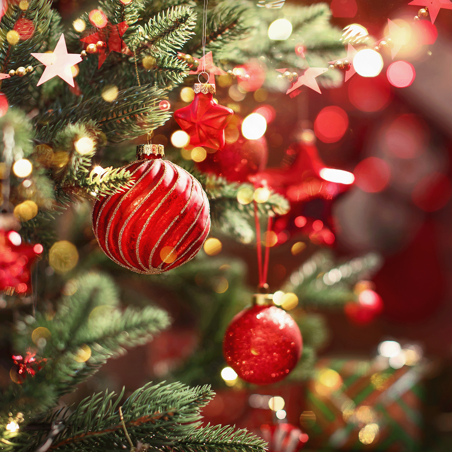 Close-up of a decorated Christmas tree with red and gold ornaments, stars, and pine branches, evoking the cozy ambiance of Tuscany Candle® SEASONAL's Holiday Hearth Long-Lasting Scented Jar Candle (14 oz).