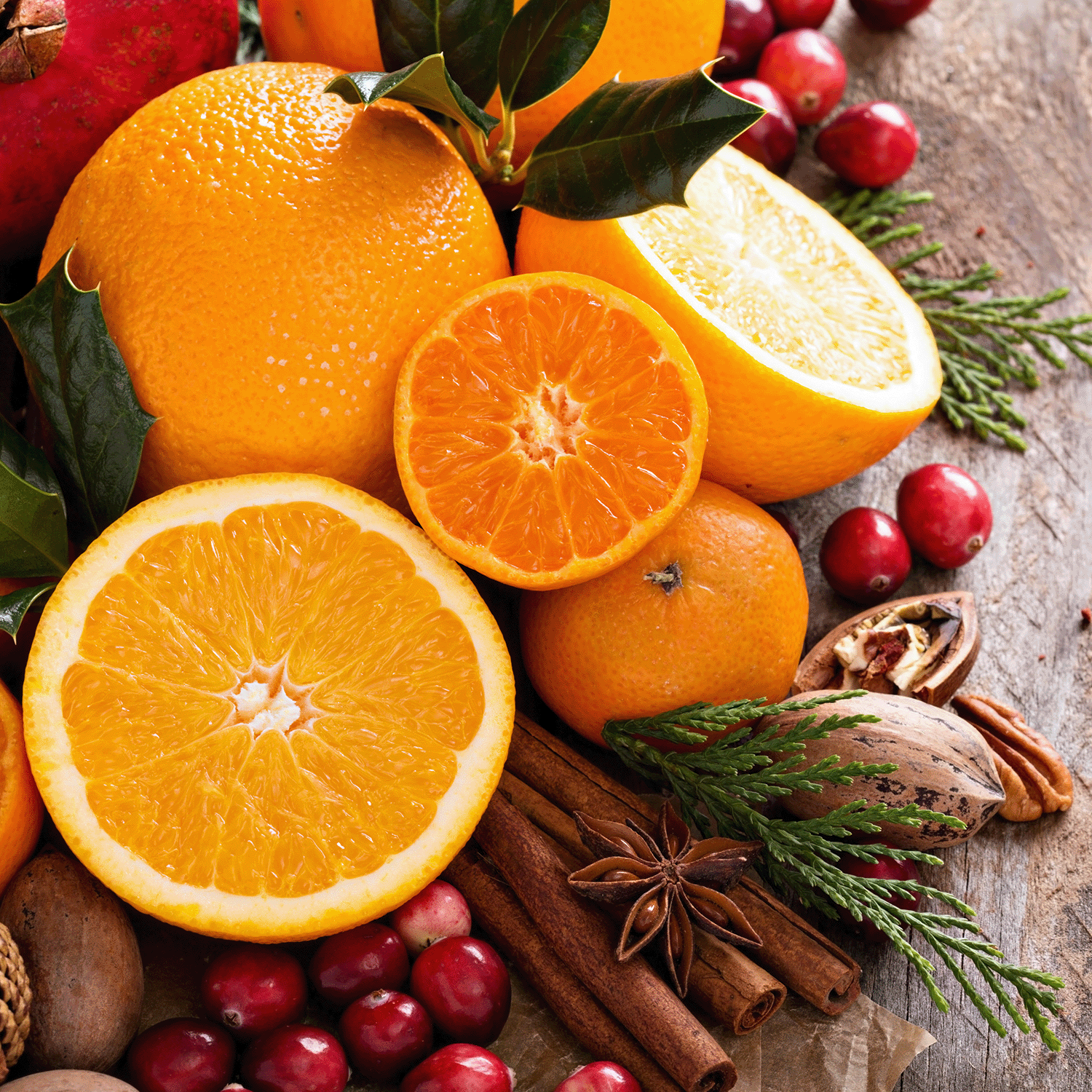 The combination of sliced oranges and tangerines among cranberries, nuts, and spices on a wooden surface captures the essence of Tuscany Candle® SEASONAL's Christmas Citrus Scented Jar Candle (18 oz).