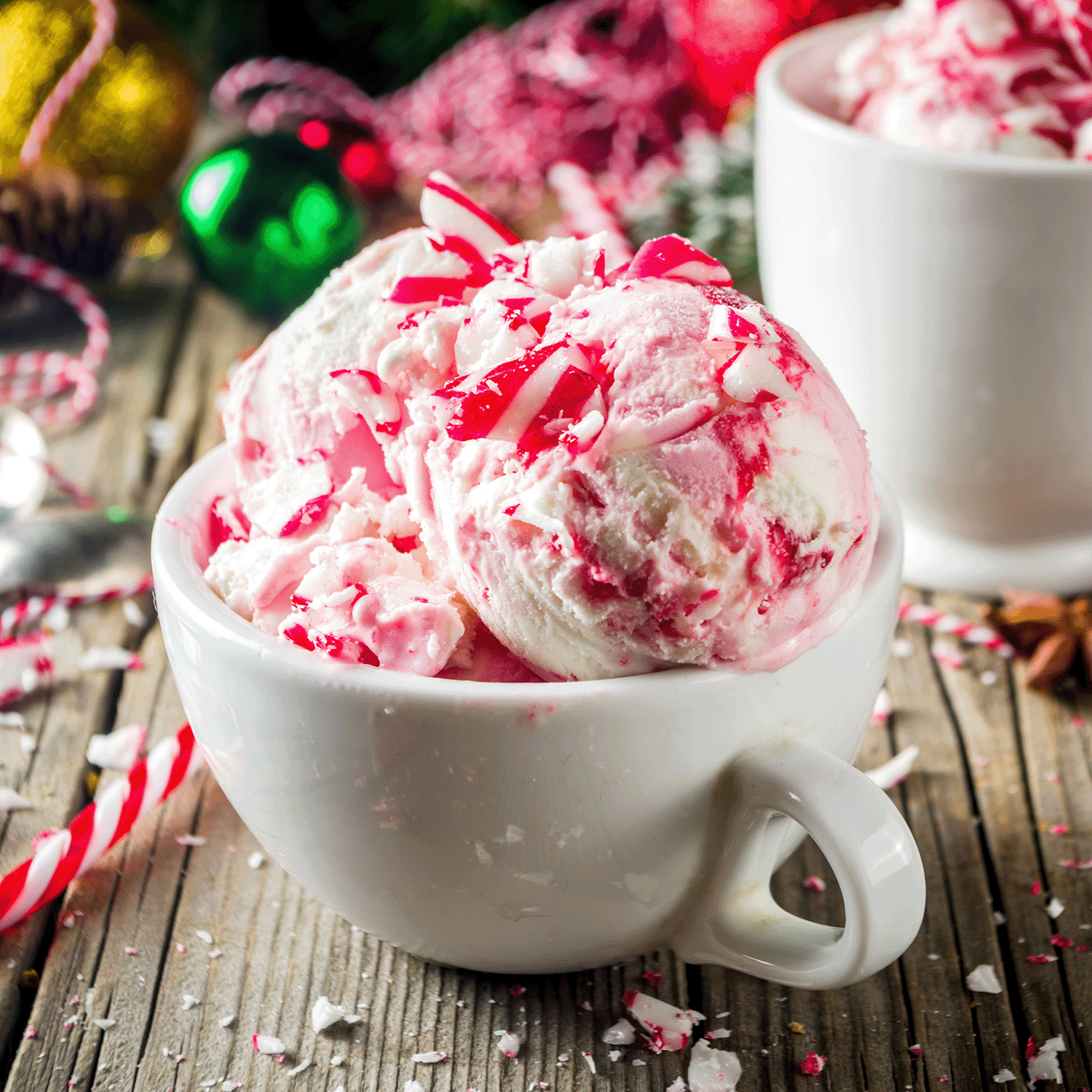 A white jar filled with the Peppermint Bark Scented Jar Candle from the Winter Flannels Collection by Tuscany Candle® SEASONAL sits on a wooden table, part of the holiday vibe, surrounded by festive decorations in the background.