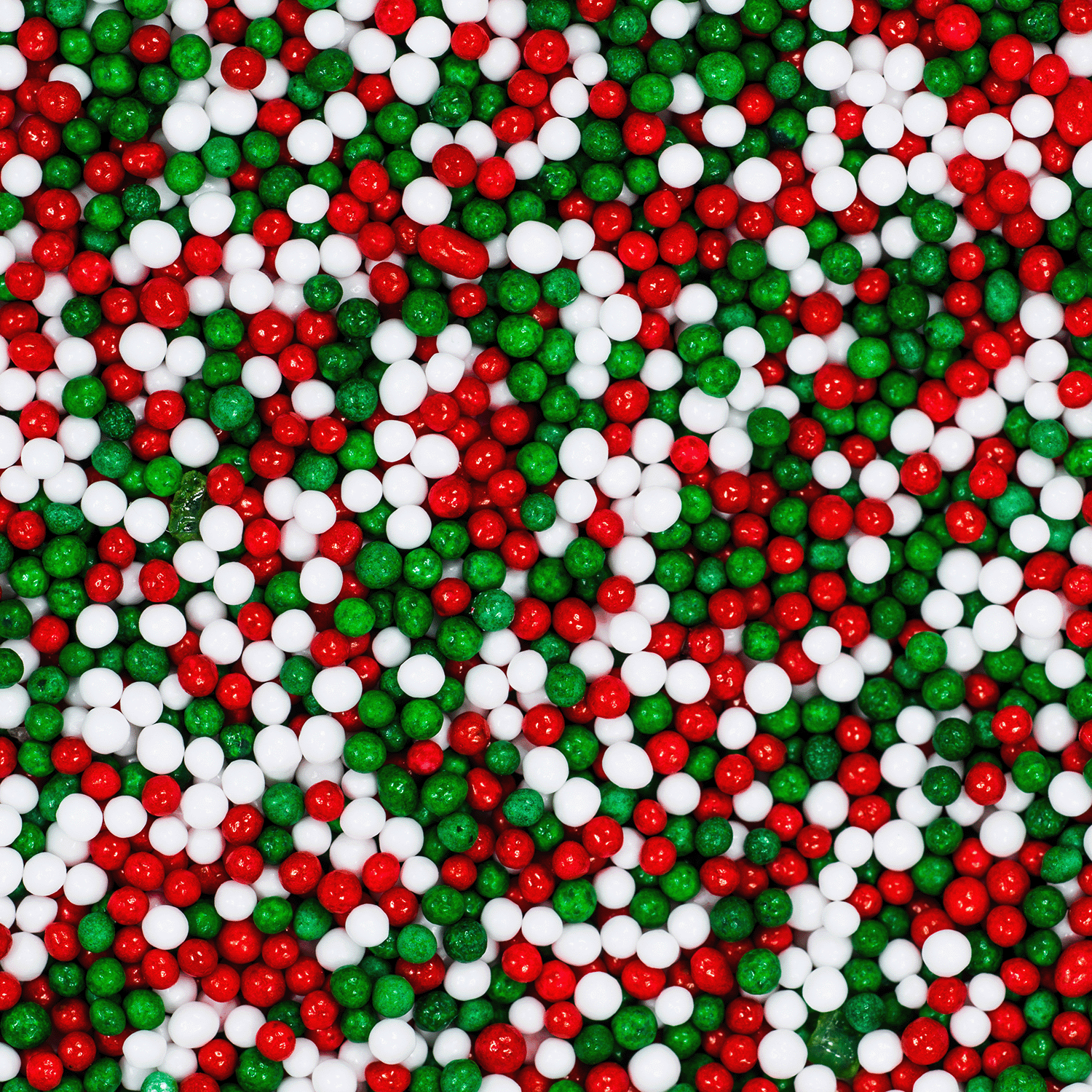 A close-up of red, green, and white candy sprinkles densely covering a surface evokes the inviting aroma of the Christmas Cookies Scented Jar Candle from the Winter Reverie Collection by Tuscany Candle® SEASONAL, reminiscent of holiday baking.