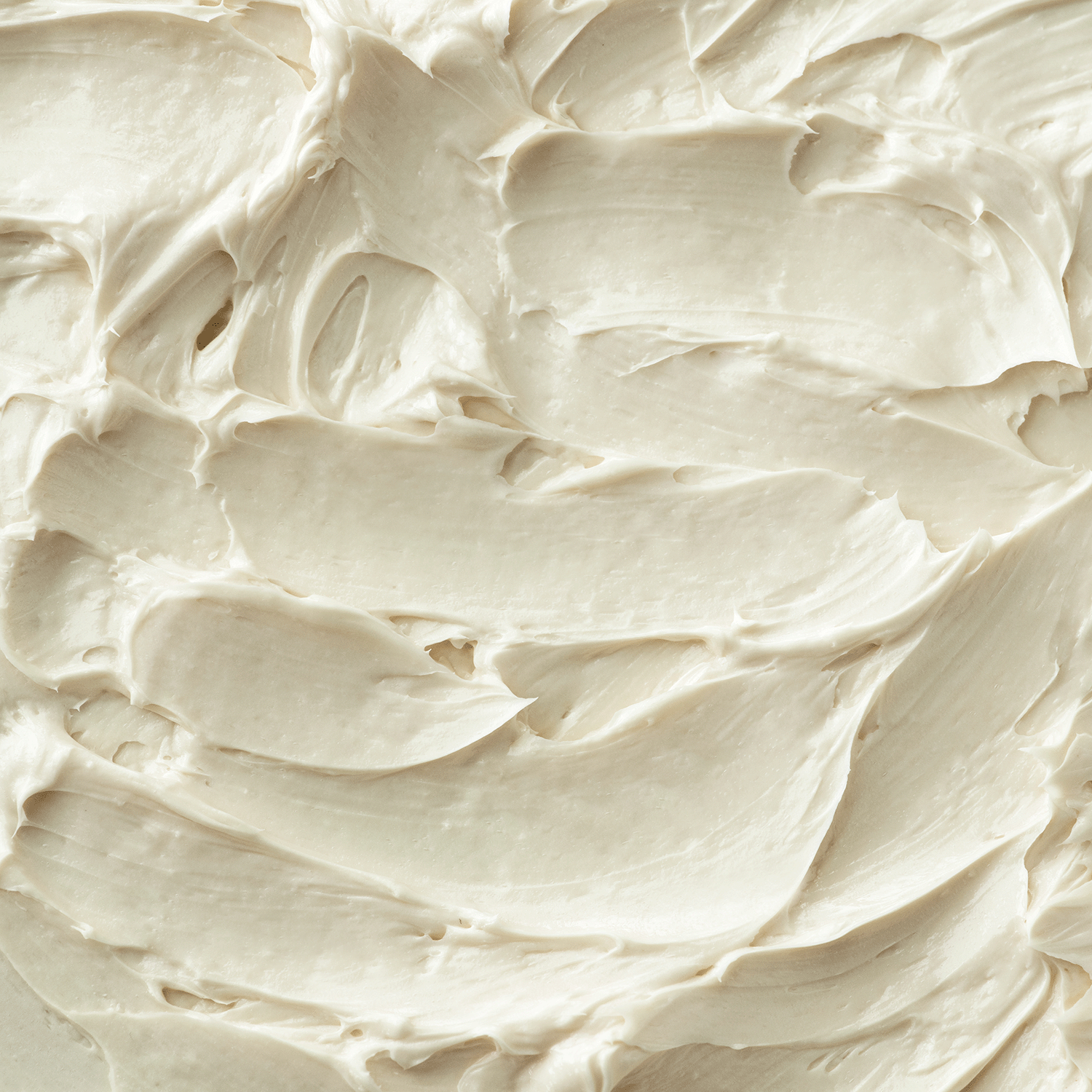 Close-up of the smooth, creamy white textured surface of the Spiced Buttercream Apples Scented Jar Candle by Tuscany Candle® SEASONAL, with swirling patterns reminiscent of its gentle glow, enhancing the festive atmosphere.