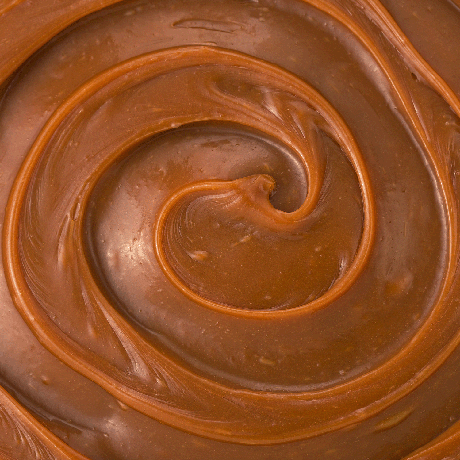 Close-up of the glossy, smooth swirl on Tuscany Candle® SEASONAL’s Fall Feels: Amber Woods & Orchard Apple Scented Candle (14 oz), revealing a rich spiral in warm brown tones from the Simply Fall Collection.