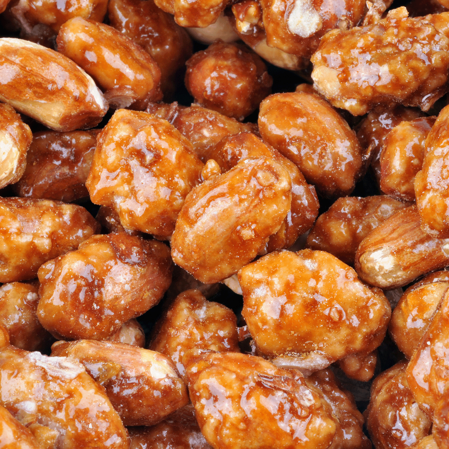 Close-up of caramelized almonds coated in glossy, brown sugar syrup—reminiscent of the sweet aroma from Tuscany Candle® SEASONAL’s Enchanted Pralines: Maple Syrup & Spice Scented Holiday Candle (18 oz) filling your home.