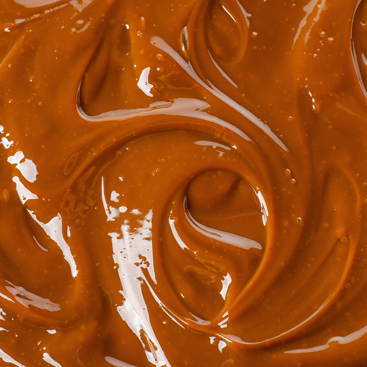 Close-up of smooth, glossy caramel swirls, evoking the warm sweetness of Tuscany Candle® SEASONAL Milk for Santa Scented Holiday Candle (14 oz).