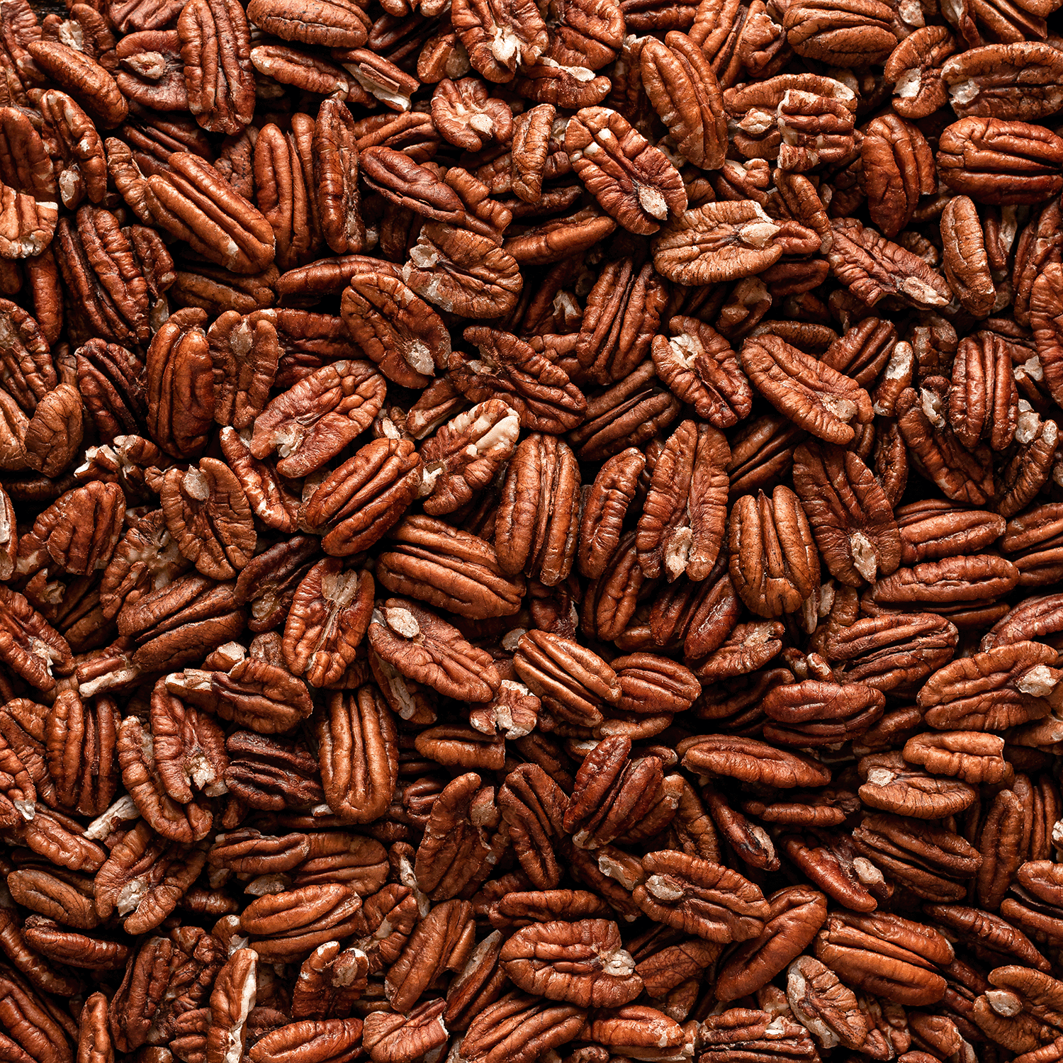 A close-up of shelled pecans with their rich brown, wrinkled surfaces—perfect for enjoying alongside a Tuscany Candle® SEASONAL Christmas Morning Scented Holiday Candle (14 oz) during cozy holiday gatherings.