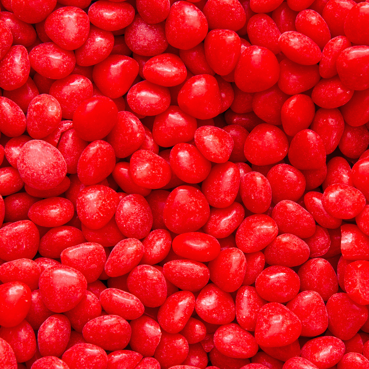 Close-up of Tuscany Candle® SEASONAL Red Hot Hearts, an 18 oz red hot cinnamon-scented Valentine's candle with a dense, textured surface formed by shiny, red, heart-shaped wax pieces.