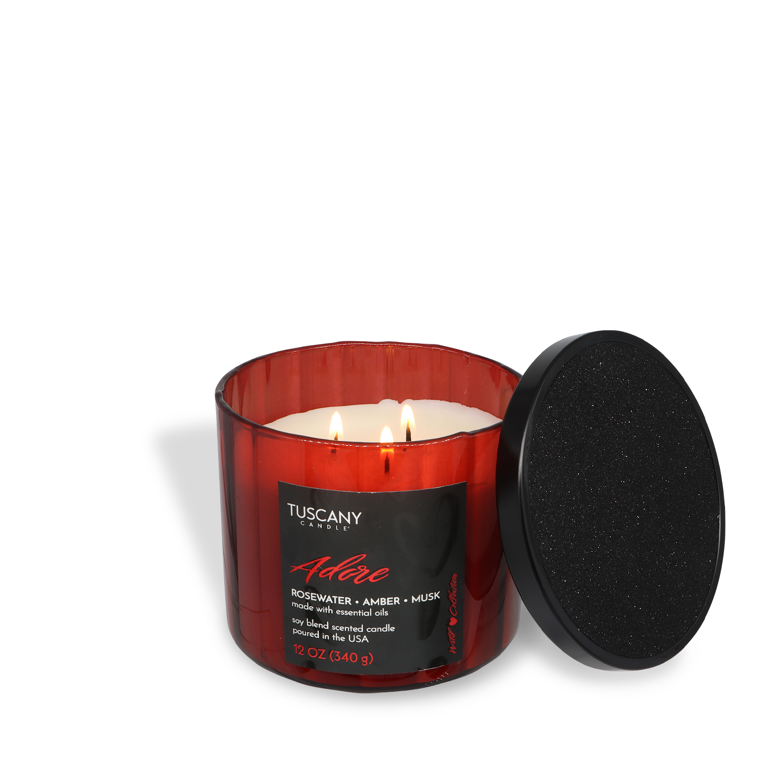 A red glass jar candle labeled "Adore: Rosewater & Amber" by Tuscany Candle® SEASONAL, with two lit wicks and a black lid beside it.