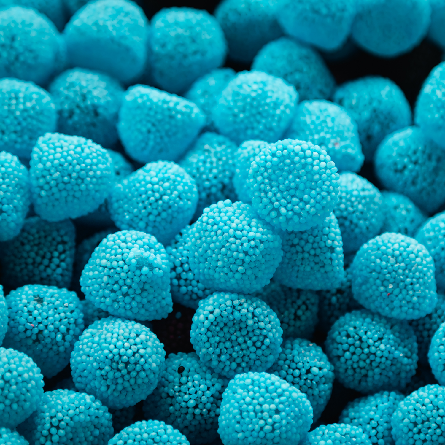 Close-up of Tuscany Candle® SEASONAL's Sour Blue Raspberry: Cherry & Lime Scented Summer Candle (12 oz), highlighting its vibrant blue color inspired by sour blue raspberry treats.