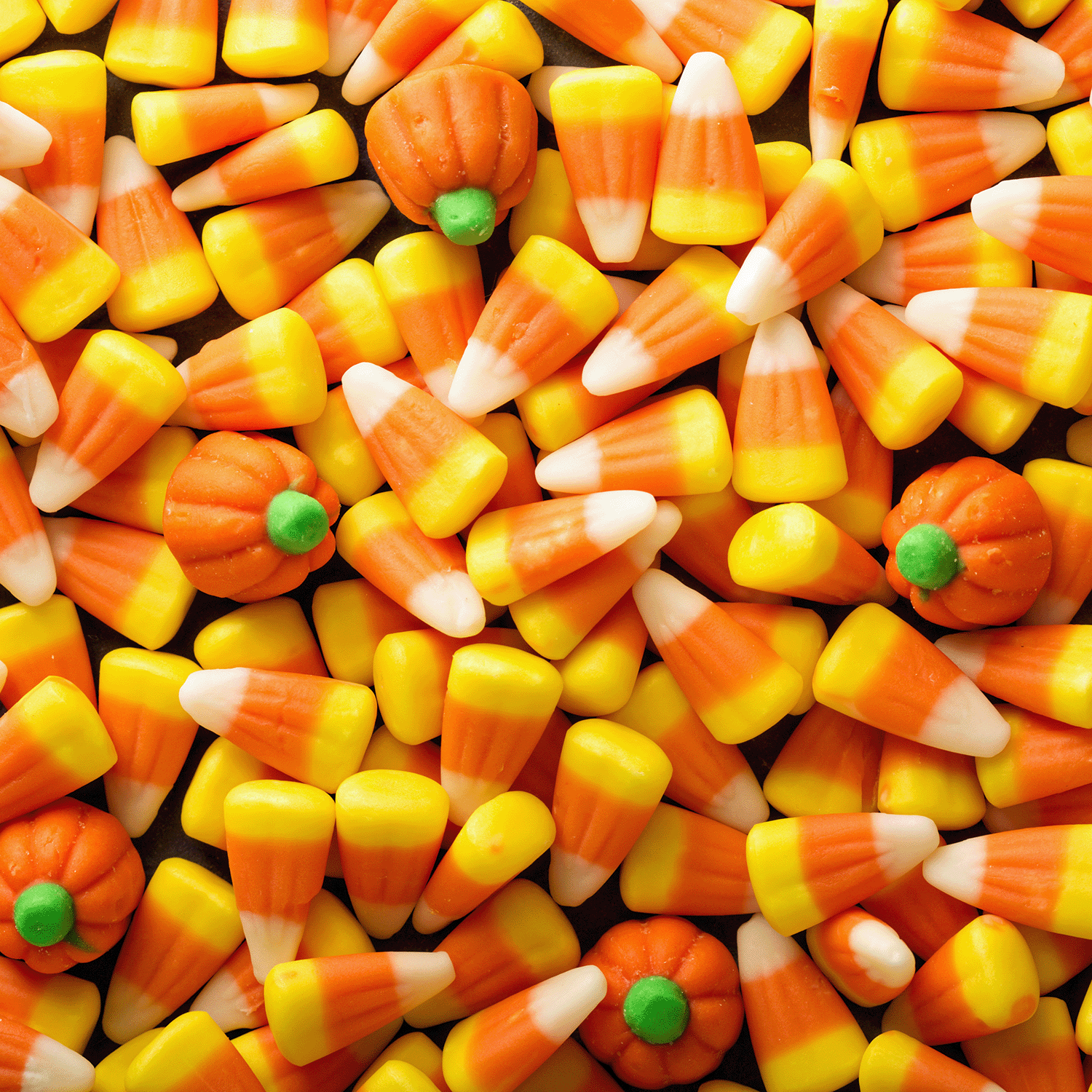 Tuscany Candle® SEASONAL Candy Corn: Buttery Vanilla Scented Halloween Wax Melts (2.5 oz), featuring festive orange, yellow, and white colors, are scattered across a flat surface.