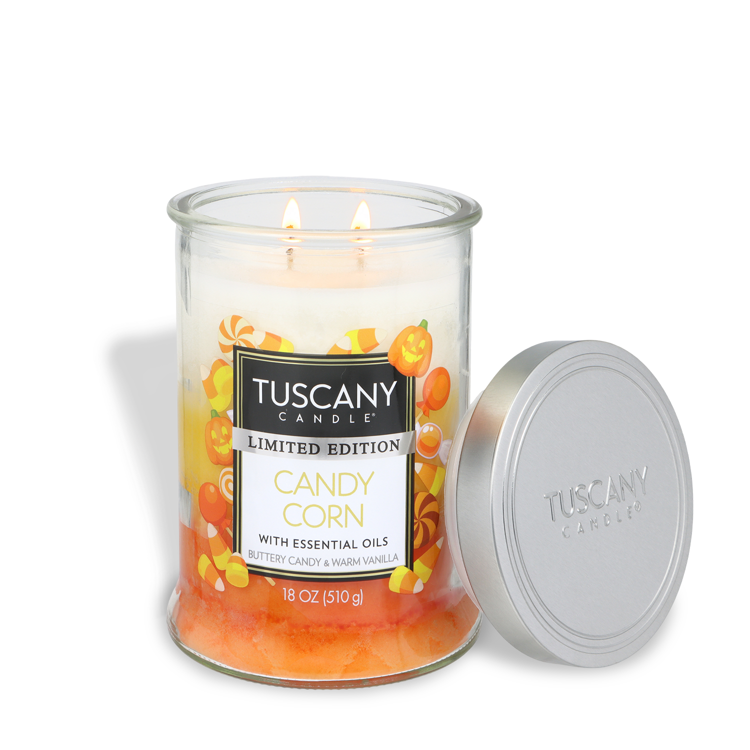 An 18 oz Tuscany Candle® SEASONAL “Candy Corn: Buttery Candy & Vanilla Scented Halloween Candle,” featuring two lit wicks, sits beside a silver lid. The glass jar is adorned with images of candy corn and pumpkins.