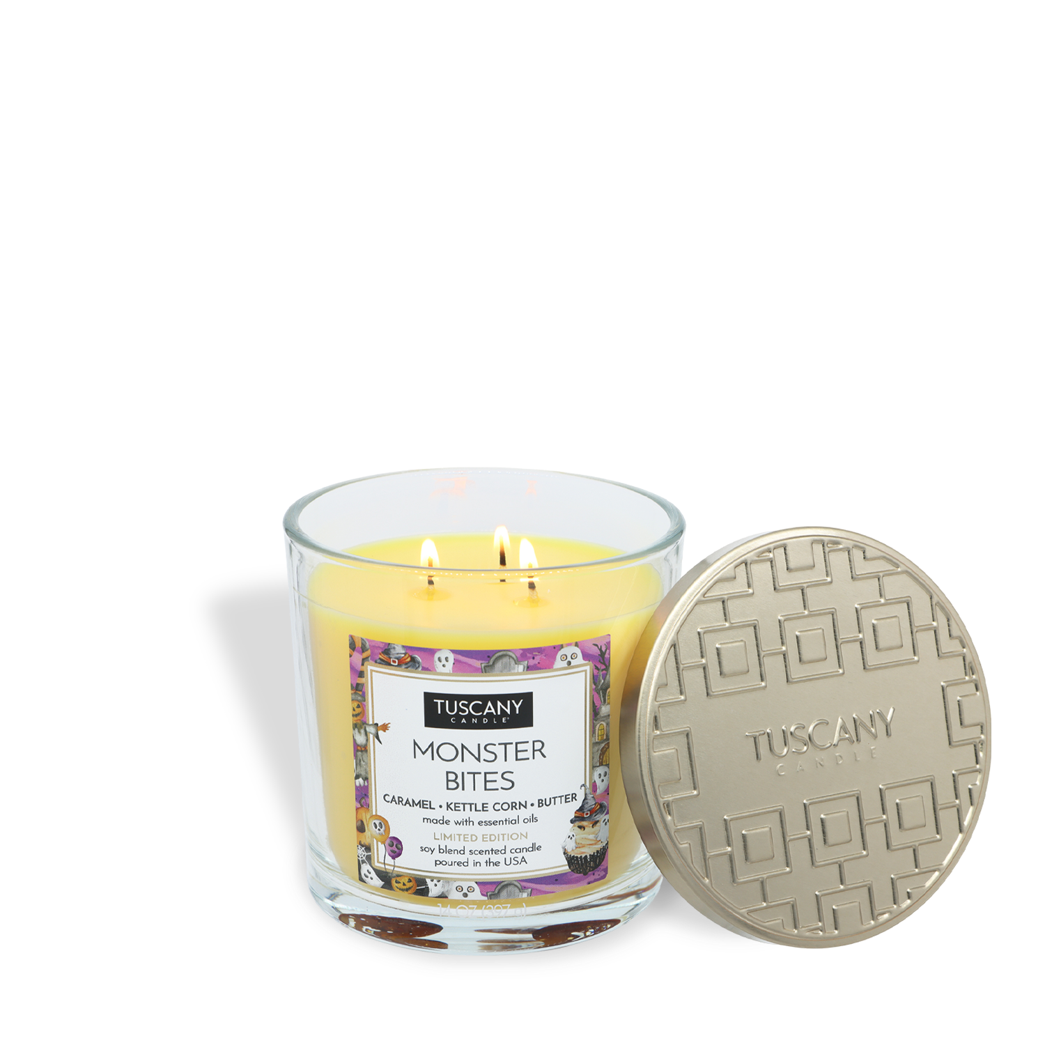 A yellow “Monster Bites: Caramel Kettlecorn Scented Halloween Candle” (14 oz) by Tuscany Candle® SEASONAL, featuring two wicks in a glass jar with a gold-patterned lid resting against it.