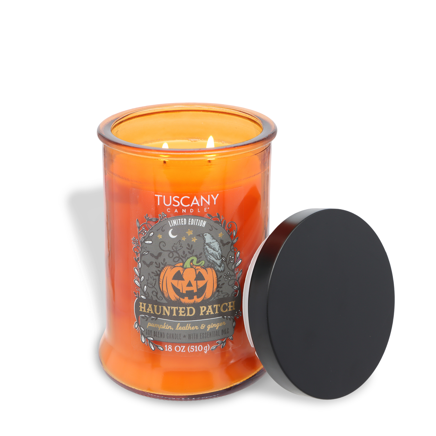 A Tuscany Candle® SEASONAL “Haunted Patch: Pumpkin, Leather & Ginger Scented Halloween Candle” (18 oz) sits with its black lid removed, revealing two lit wicks. The orange candle’s label displays a pumpkin and festive Halloween-themed design.