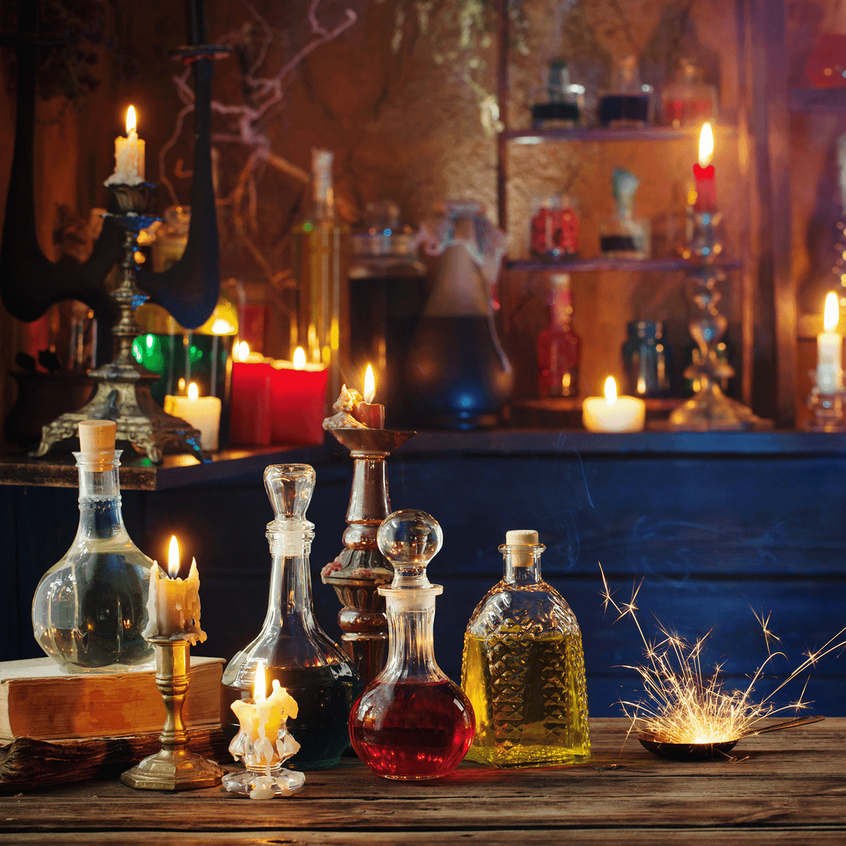 On a wooden table illuminated by the glow of lit candles and sparkling lights, Cauldron Boil: Smoked Cherry & White Woods Scented Halloween Candles from Tuscany Candle® SEASONAL (18 oz) are arranged among glass bottles filled with vibrant liquids; additional candles and bottles line the shelves in the background.