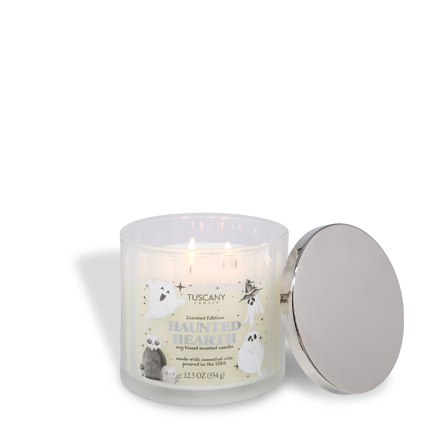 A lit Tuscany Candle® SEASONAL “Haunted Hearth: Apple & Citrus Zest Scented Halloween Candle” (12.5 oz) with three wicks and ghosts on the jar, its silver lid resting beside it.