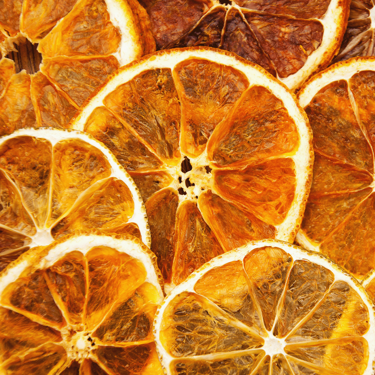Close-up of overlapping dried orange slices highlights the textured, translucent segments in shades of orange and brown, capturing the essence of Tuscany Candle® SEASONAL’s Haunted Hearth: Apple & Citrus Zest Scented Halloween Candle (12.5 oz).