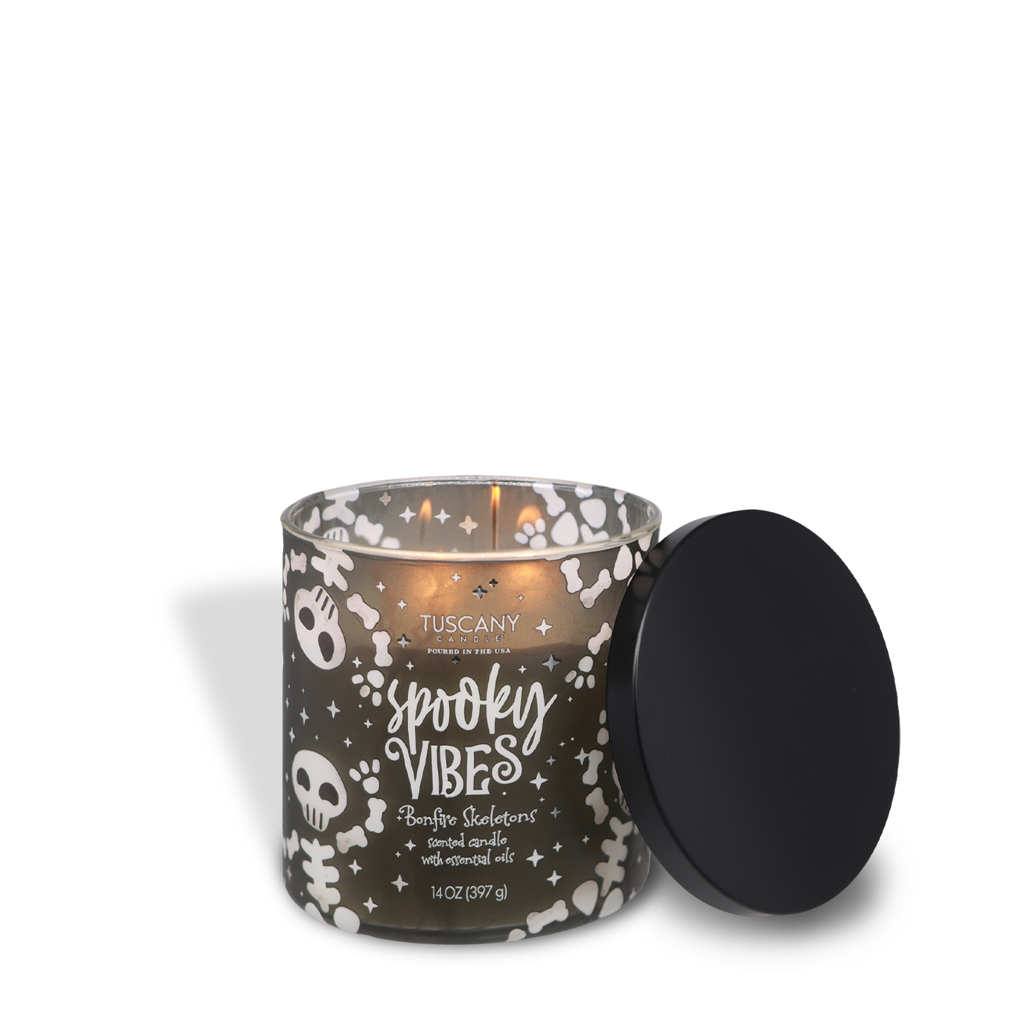 A lit Tuscany Candle® SEASONAL “Spooky Vibes: Bonfire Skeletons” scented Halloween candle (14 oz) glows in a black container decorated with skeleton designs, while the lid rests nearby.