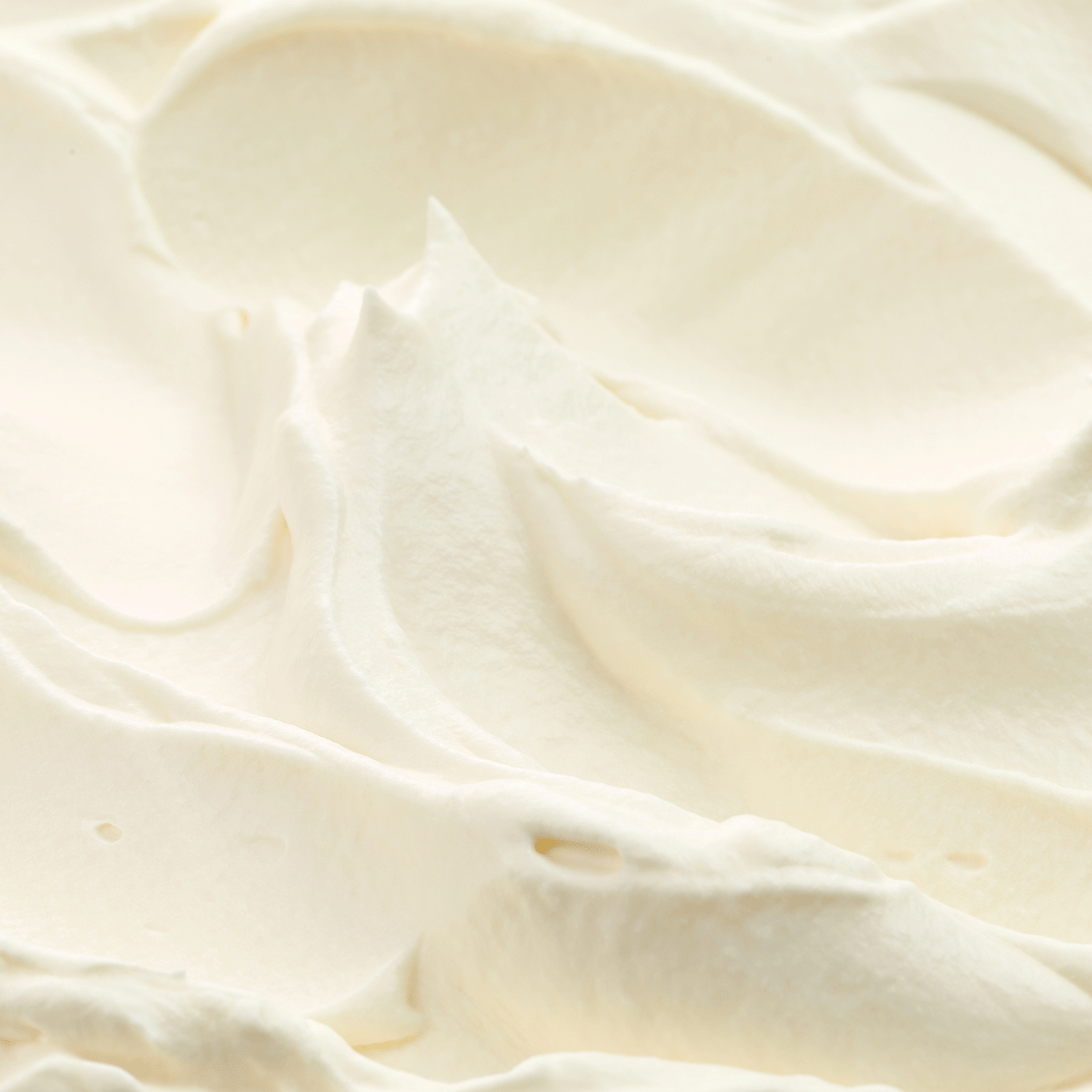 Close-up of the smooth, creamy white whipped surface of Tuscany Candle® SEASONAL's "Cinnamon Rolls: Icing & Sugar Scented Fall Wax Melt" (2.5 oz), with soft peaks and gentle shadows—evoking the cozy autumn aroma of freshly baked cinnamon rolls right at home.