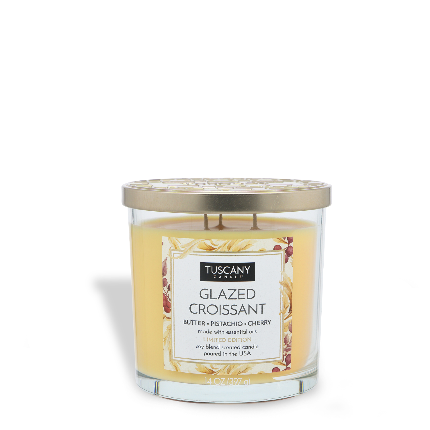 The Tuscany Candle® SEASONAL Glazed Croissant: Butter & Pistachio Scented Fall Candle (14 oz) comes in a glass jar with a gold metal lid and features notes of butter, pistachio, and cherry.