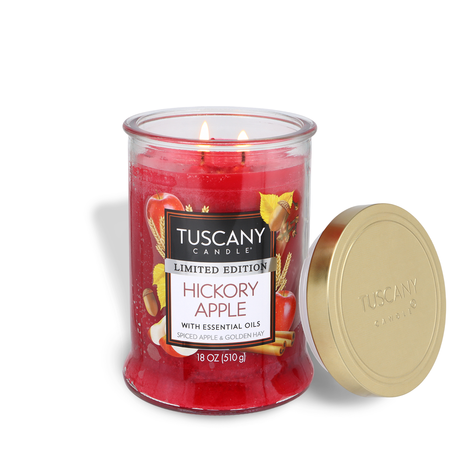 An 18 oz Tuscany Candle® SEASONAL “Hickory Apple: Spiced Apple & Golden Hay” scented fall candle with two lit wicks sits beside its gold lid on a white background.