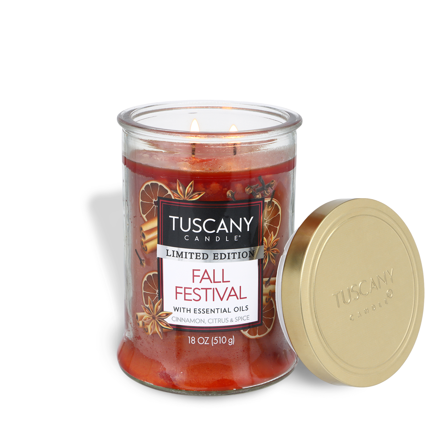 A lit Tuscany Candle® SEASONAL "Fall Festival: Cinnamon & Citrus Scented Fall Candle" (18 oz), red in color, with the lid off and beside the jar; features cinnamon, citrus, and spice scents.