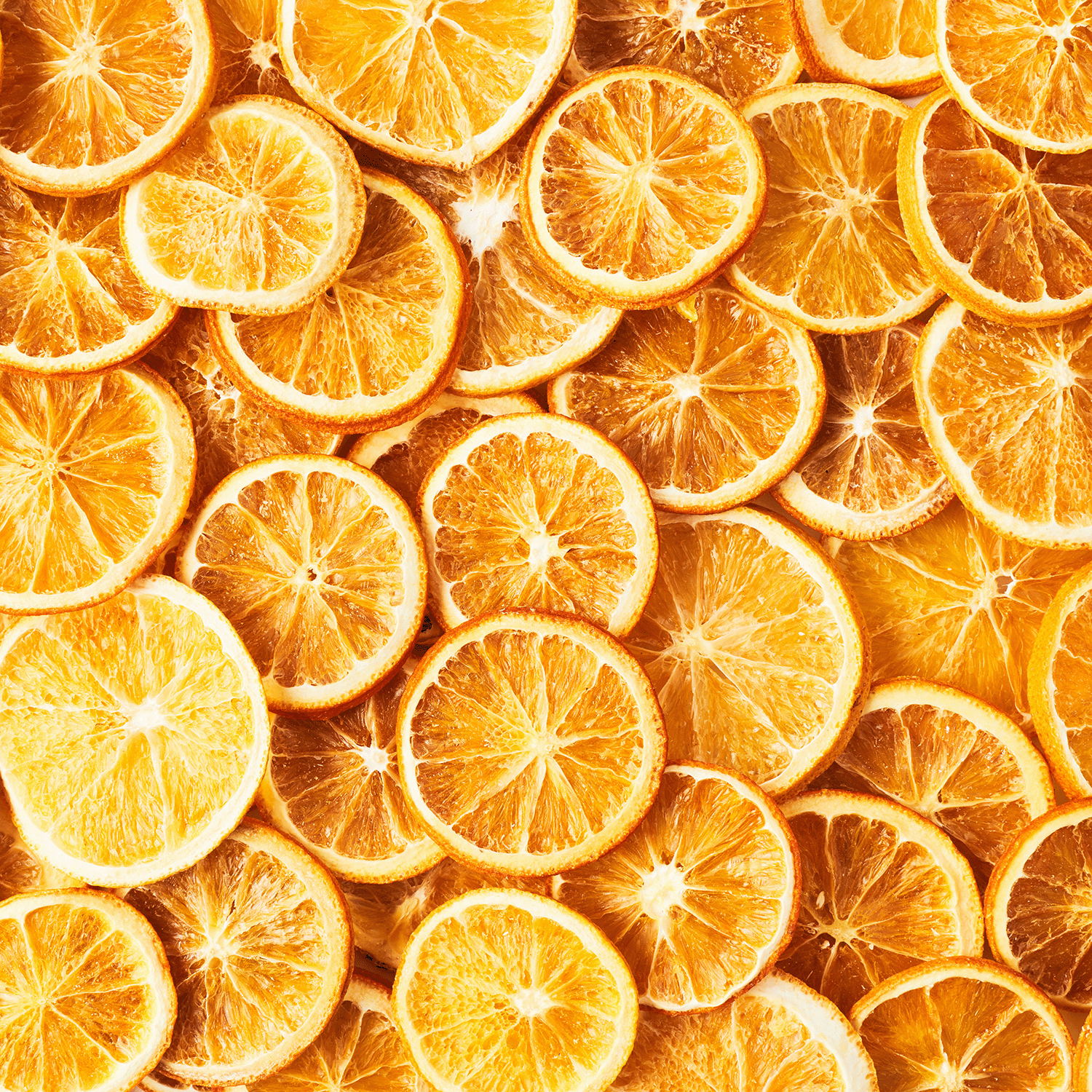 Sliced dried oranges arranged closely together, displaying vibrant circular patterns and textured rinds in warm hues of orange and yellow—perfect inspiration for the Tuscany Candle® SEASONAL Fall Festival: Cinnamon & Citrus Scented Fall Candle (18 oz), an inviting choice to create a cozy autumn atmosphere.