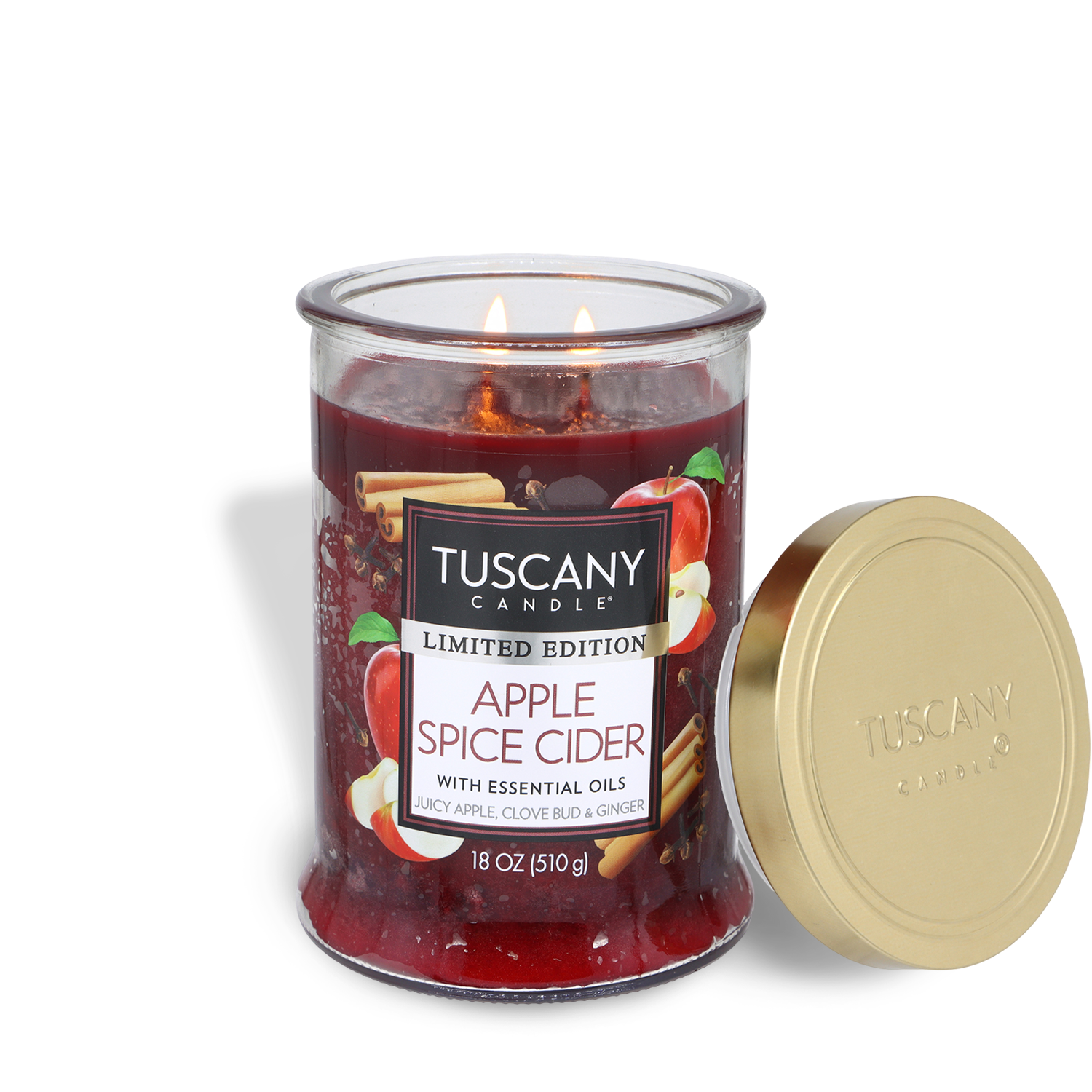 A Tuscany Candle® SEASONAL 18 oz jar labeled "Apple Spice Cider: Clove Bud & Ginger Scented Fall Candle" with a gold lid beside it. The lit candle shows images of apples on the label.