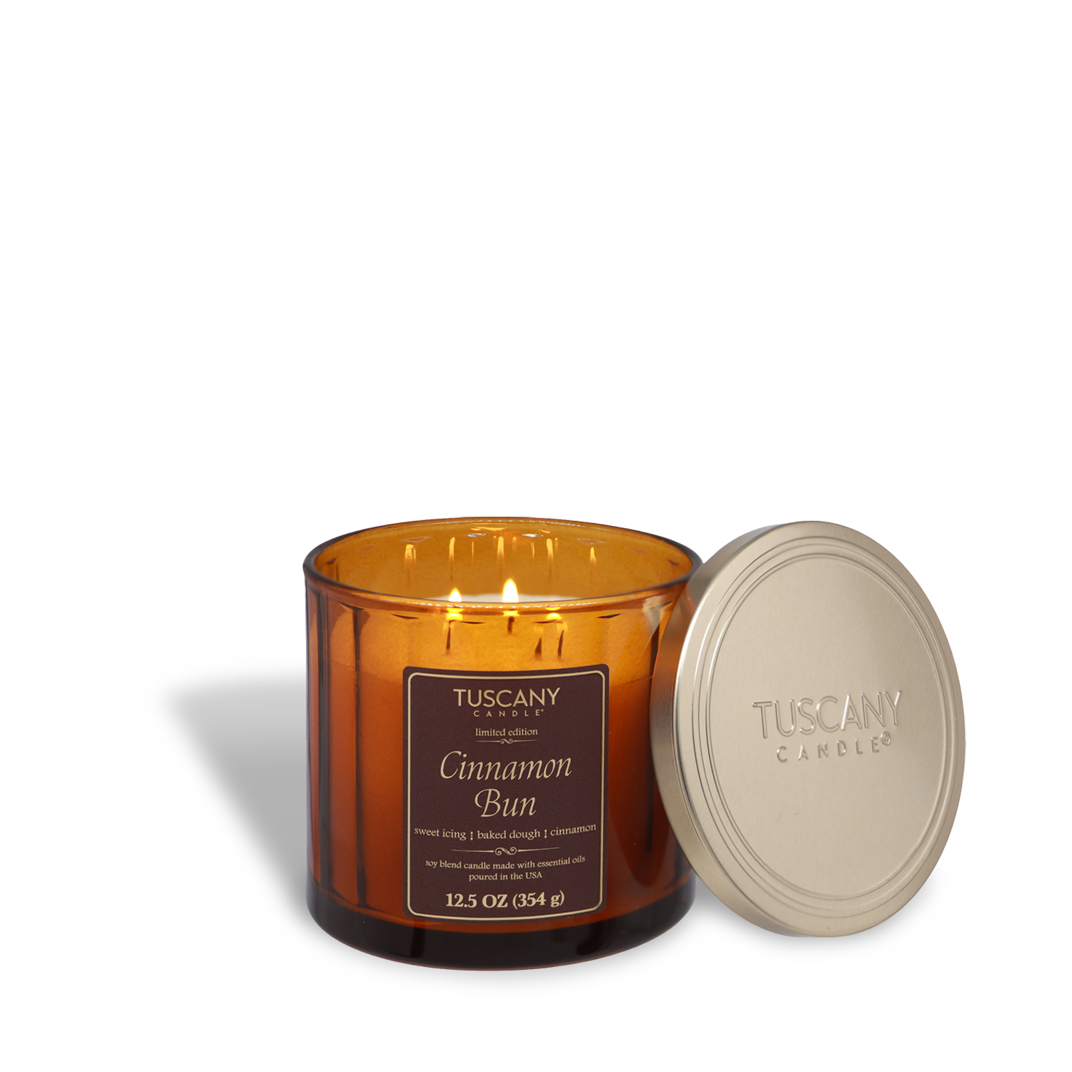 The Tuscany Candle® SEASONAL Cinnamon Bun: Icing & Dough Scented Fall Candle (12.5 oz) in an amber glass jar, with a metallic lid beside it, glows warmly and fills the room with a sweet, cozy fall fragrance.