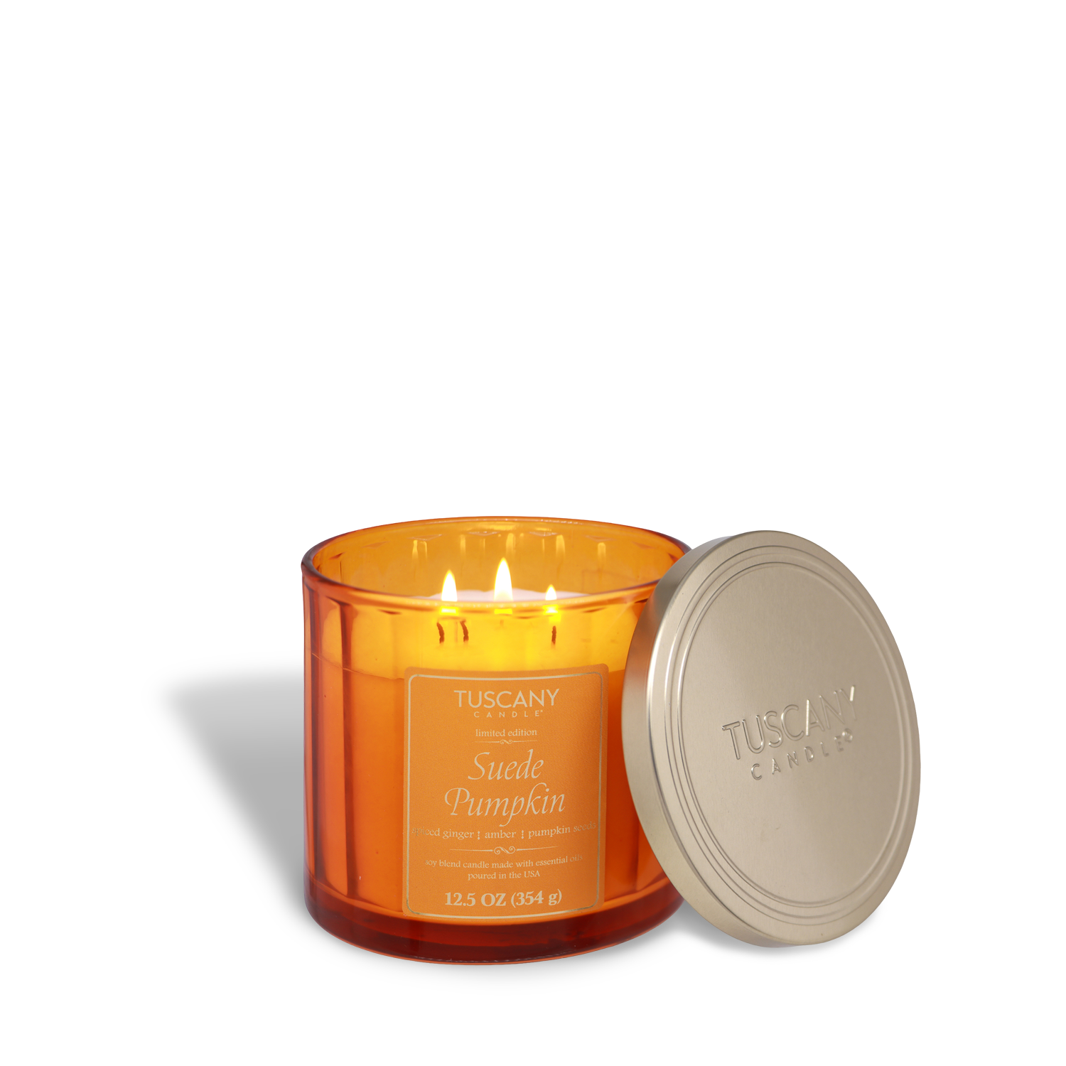 A glowing orange glass jar candle, Tuscany Candle® SEASONAL Suede Pumpkin: Ginger & Amber (12.5 oz), fills the air with cozy fall fragrance, beside a gold lid embossed with the brand.