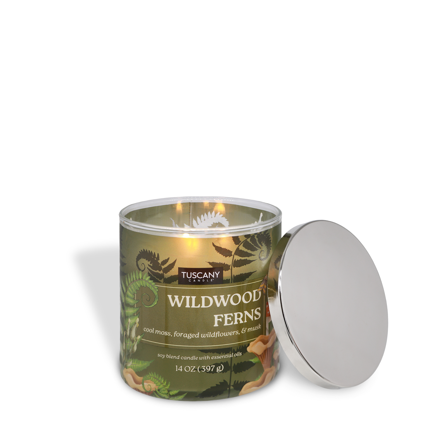 A lit Tuscany Candle® SEASONAL "Wildwood Ferns: Cool Moss & Wildflower" 14 oz candle sits with its silver lid beside it, featuring a green fern-themed label.