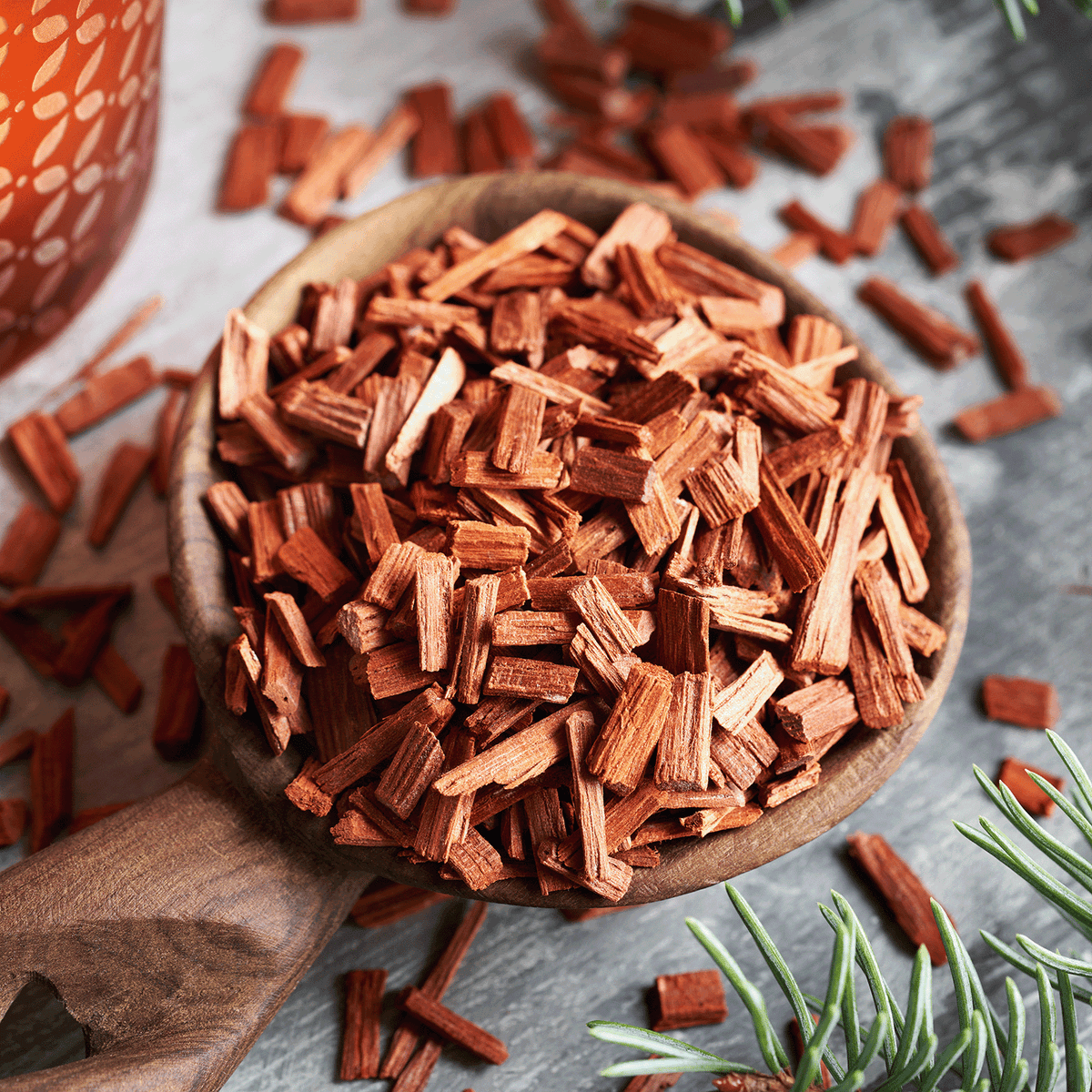A wooden scoop filled with reddish-brown wood chips for Evening Fireside®: Sandalwood & Amber Scented Holiday Wax Melt (2.5 oz).